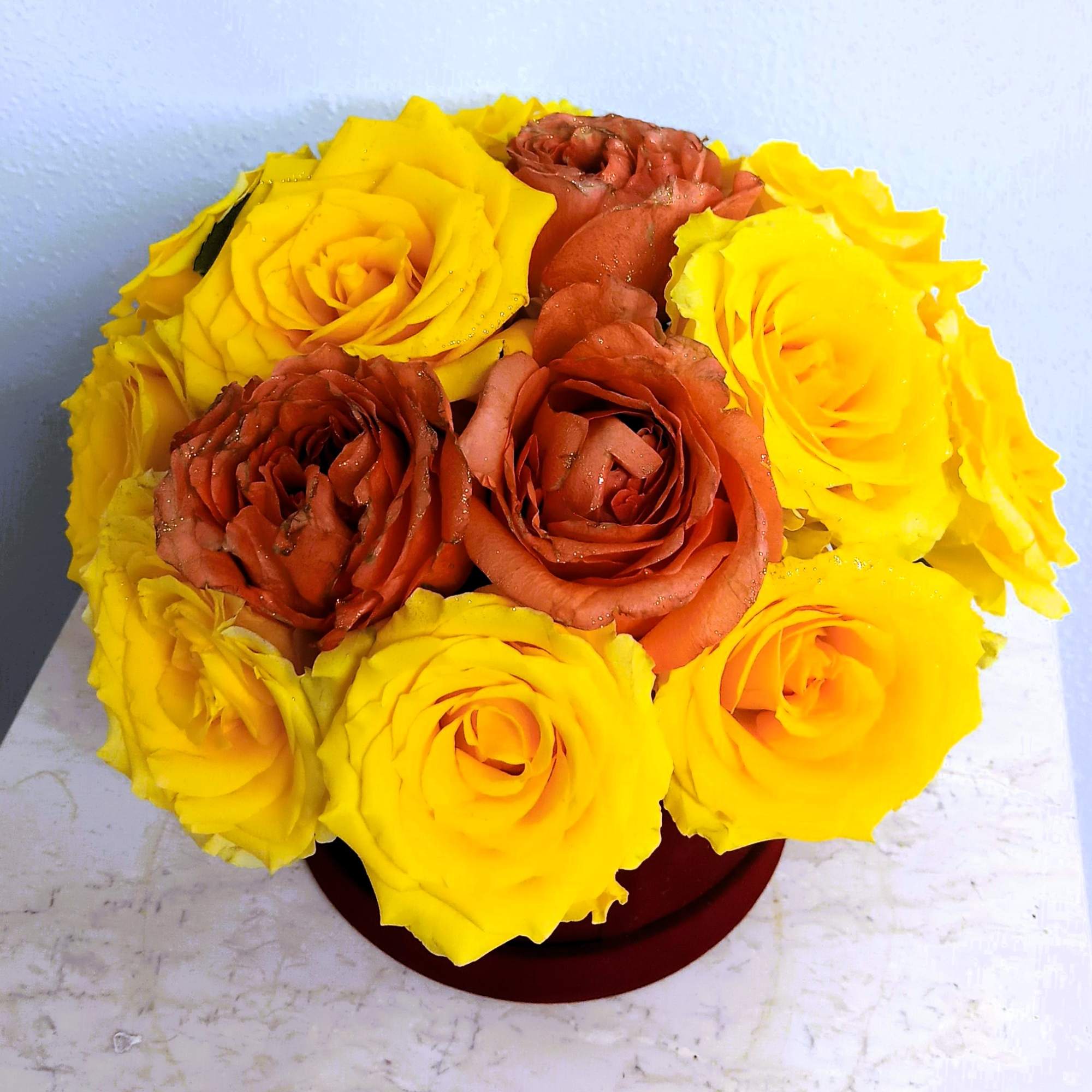 Yellow and rust-colored roses arranged in a round box