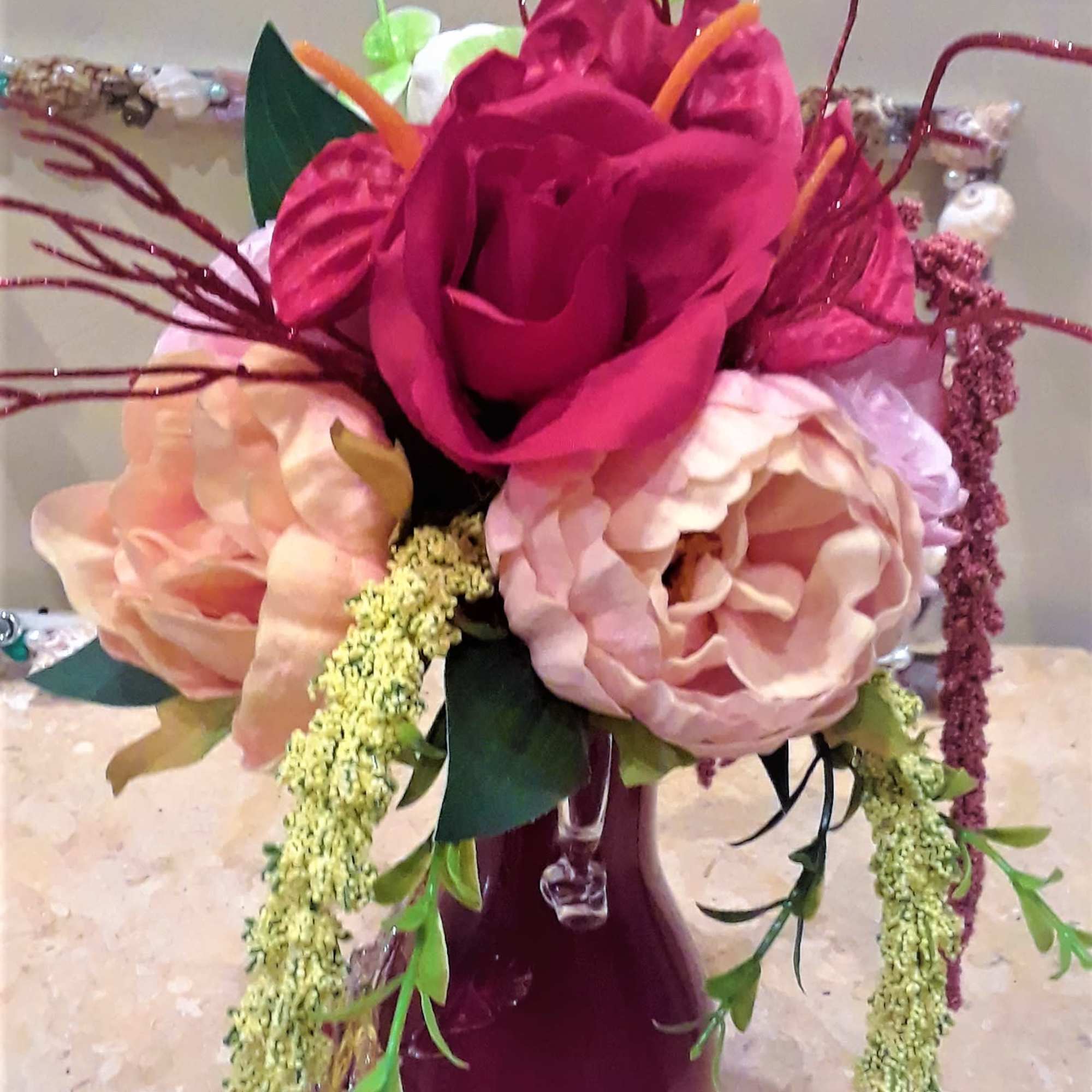 Pink and peach floral arrangement in a burgundy vase