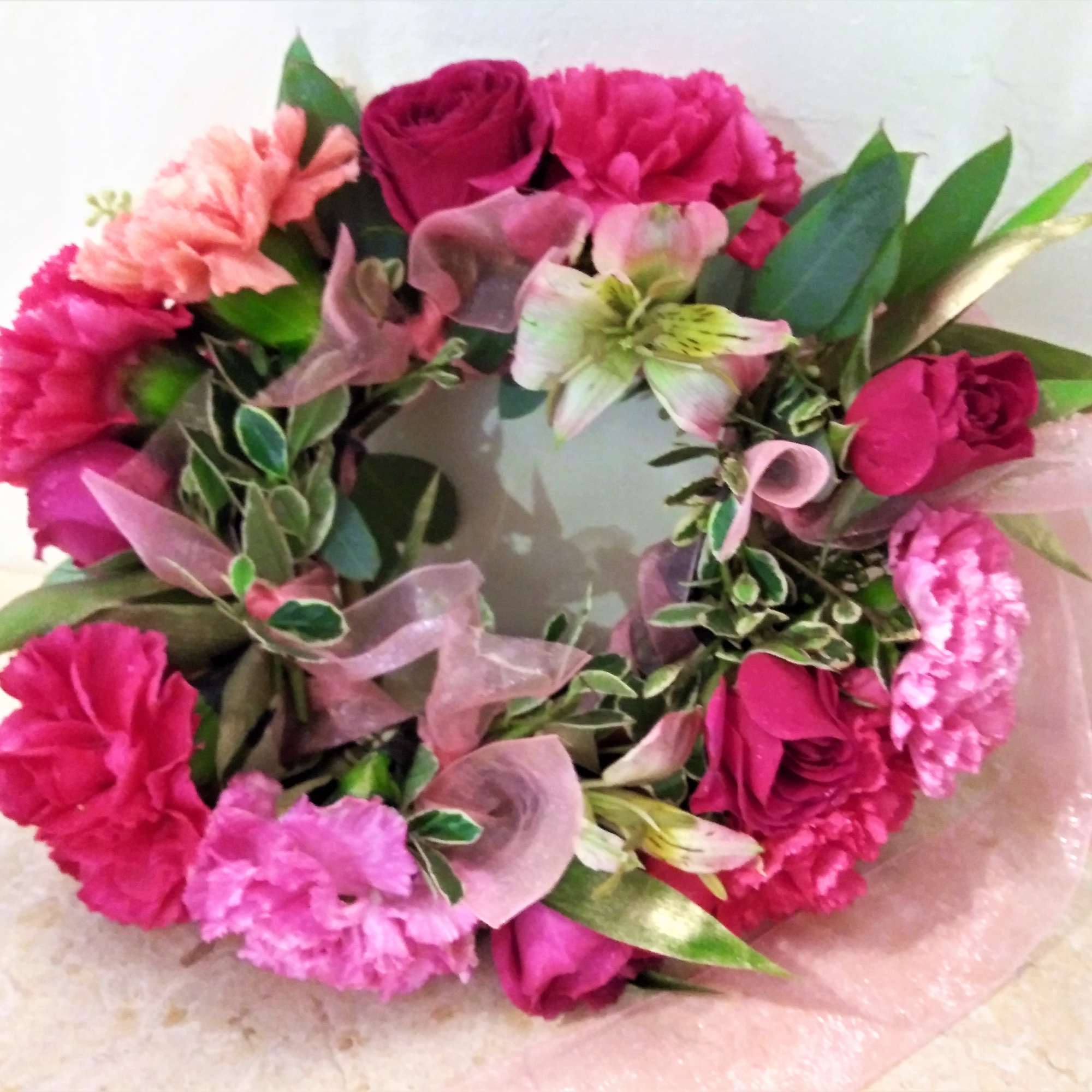 Pink floral wreath with roses and carnations on a white background