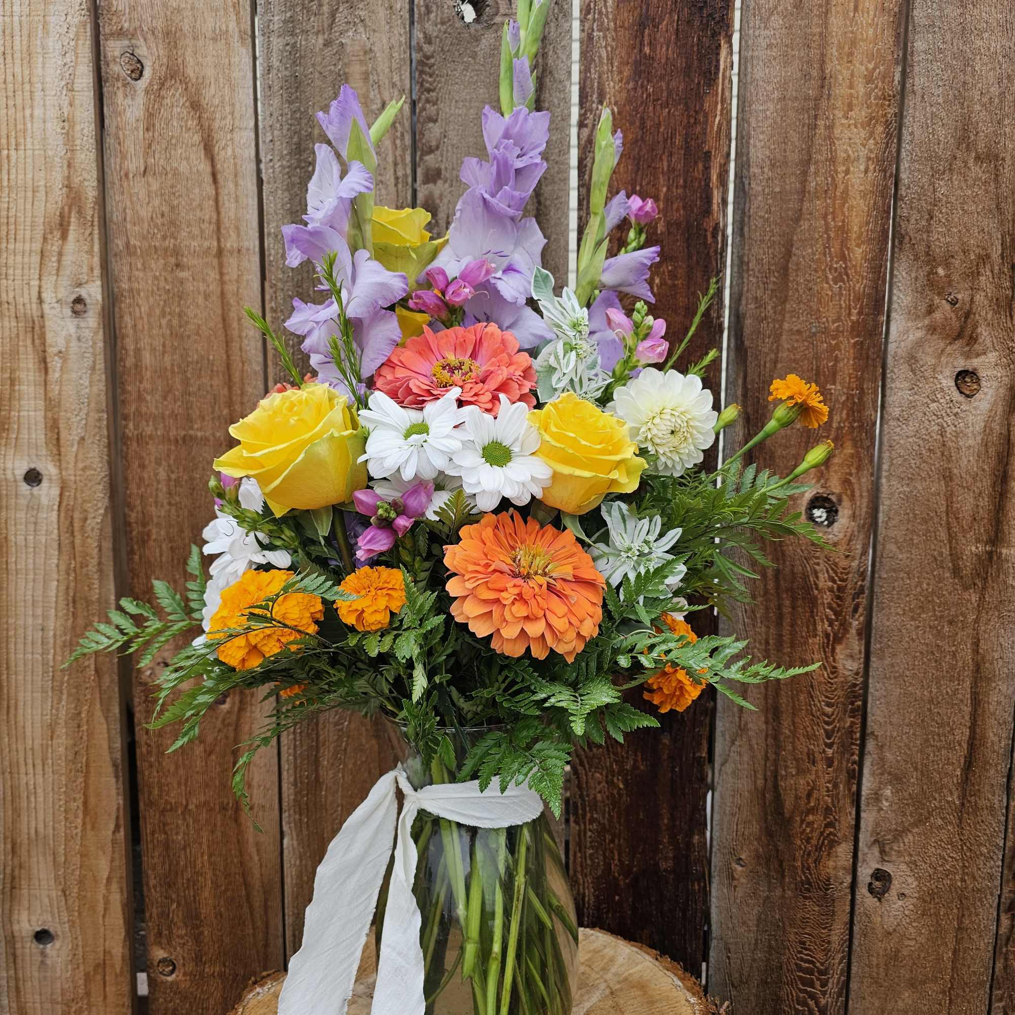 Colorful mixed bouquet in a glass vase with a white ribbon