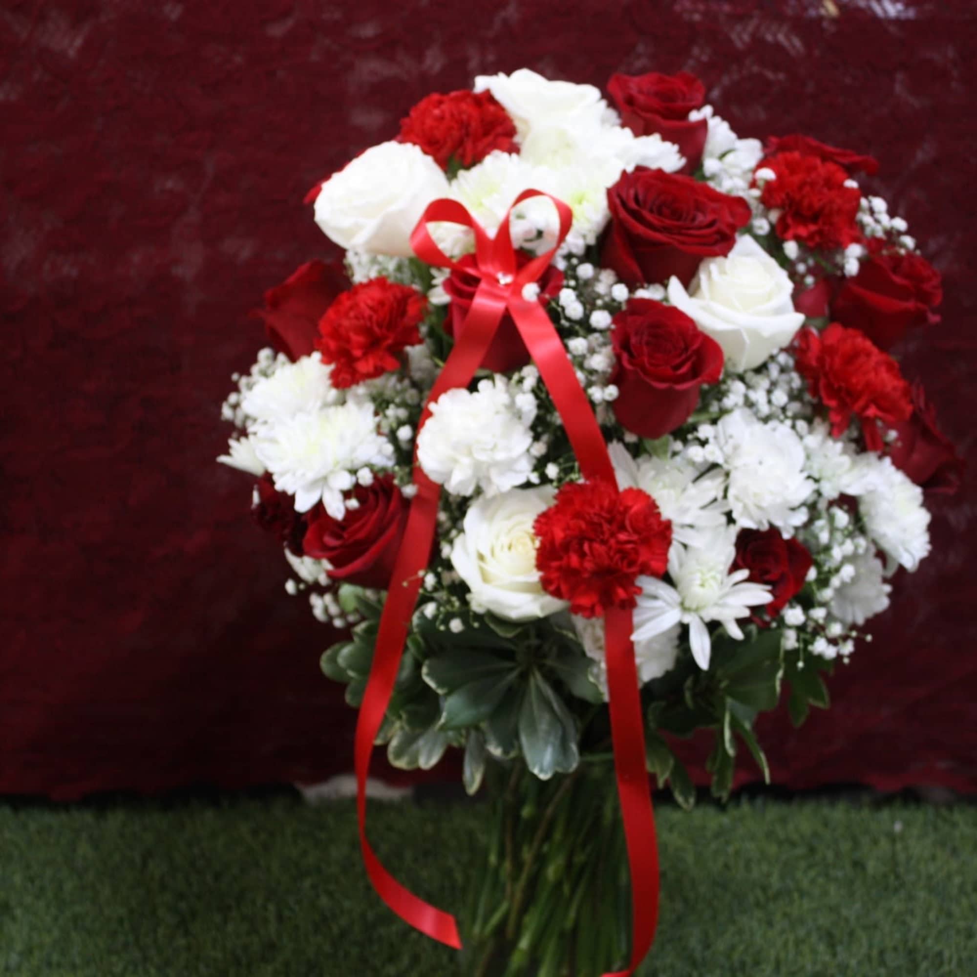 Red and white rose and carnation arrangement with a red ribbon