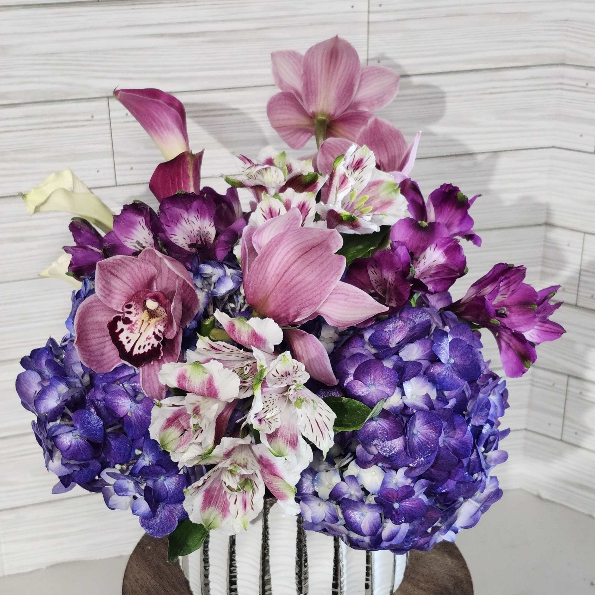 Pink and purple floral arrangement in a white vase