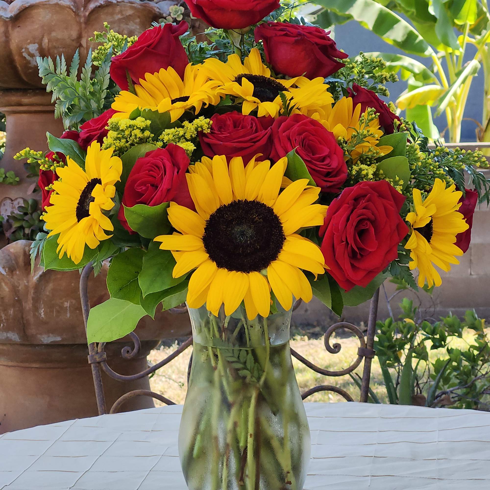 Red roses and yellow sunflowers in a glass vase