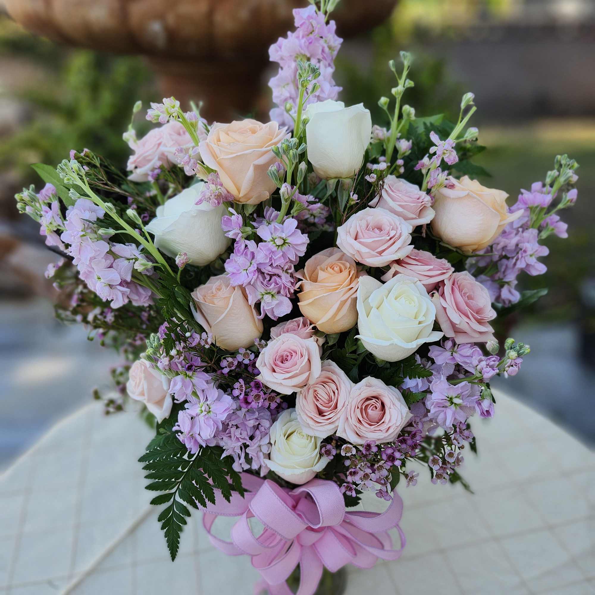 Bouquet of pink and white roses with lavender filler flowers and a pink ribbon