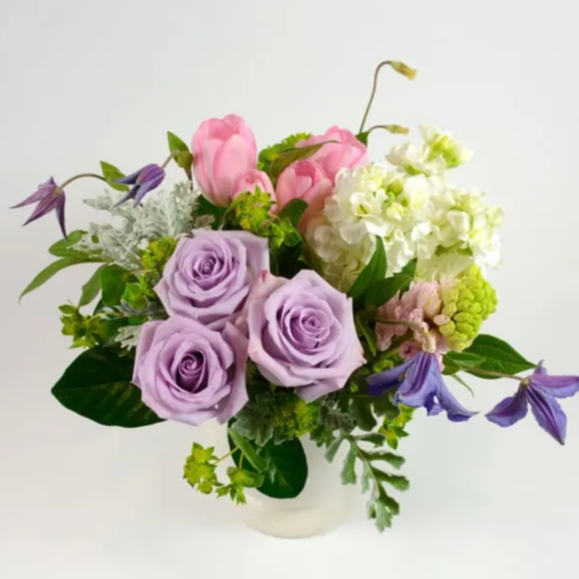 Lavender roses and pink tulips in a white vase with white hydrangea