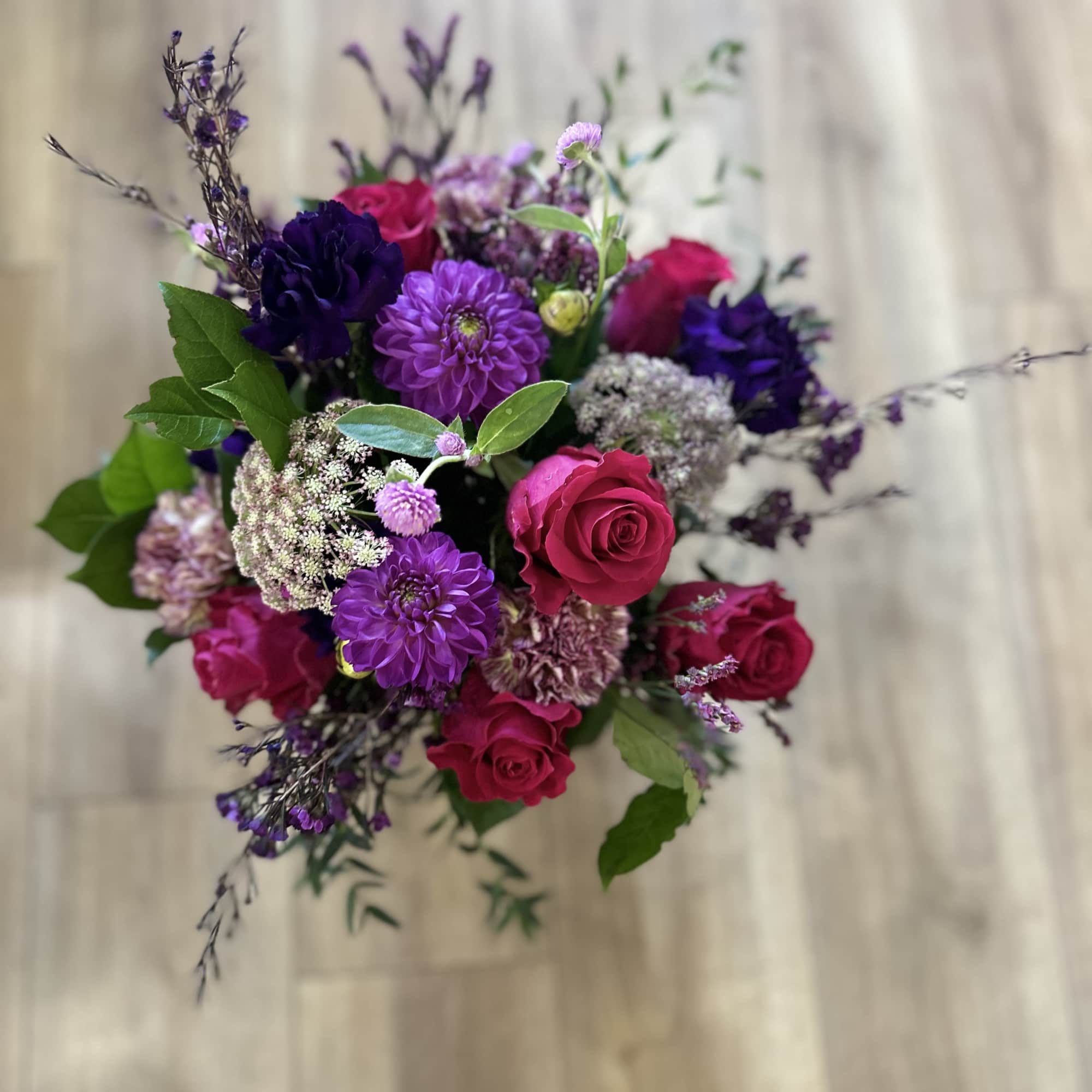 Bouquet of pink roses and purple flowers with greenery
