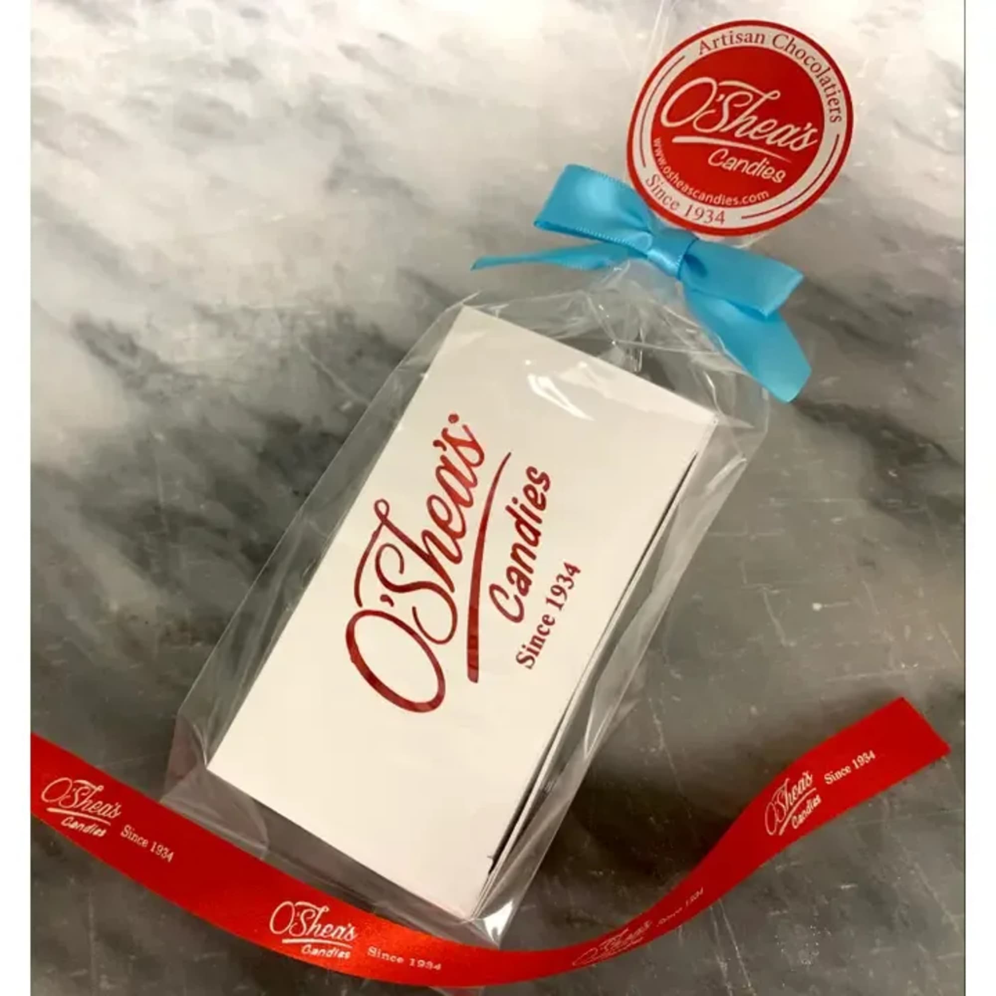 Boxed chocolates wrapped in clear plastic with a blue ribbon