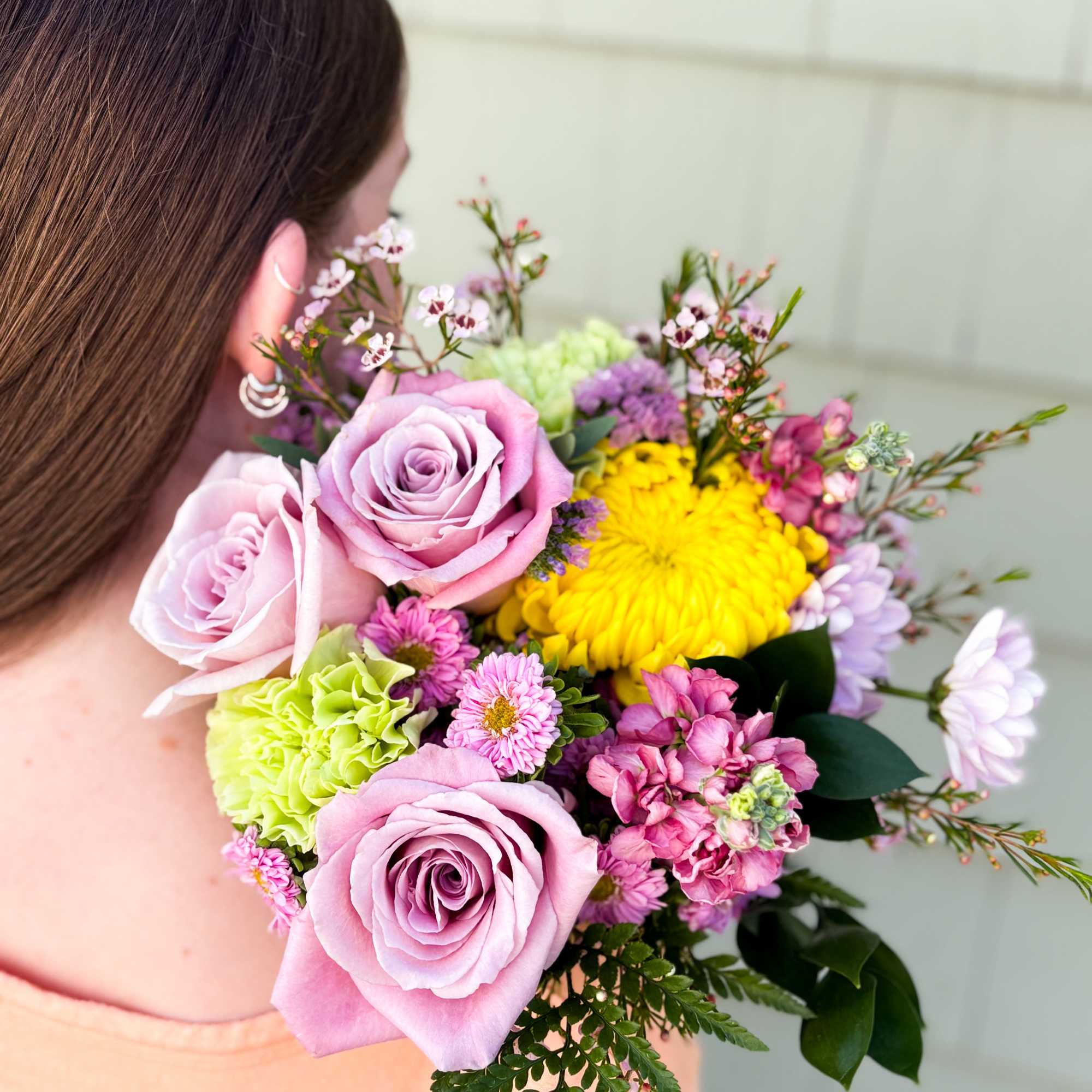 Woman holding a bouquet of pink roses and mixed flowers