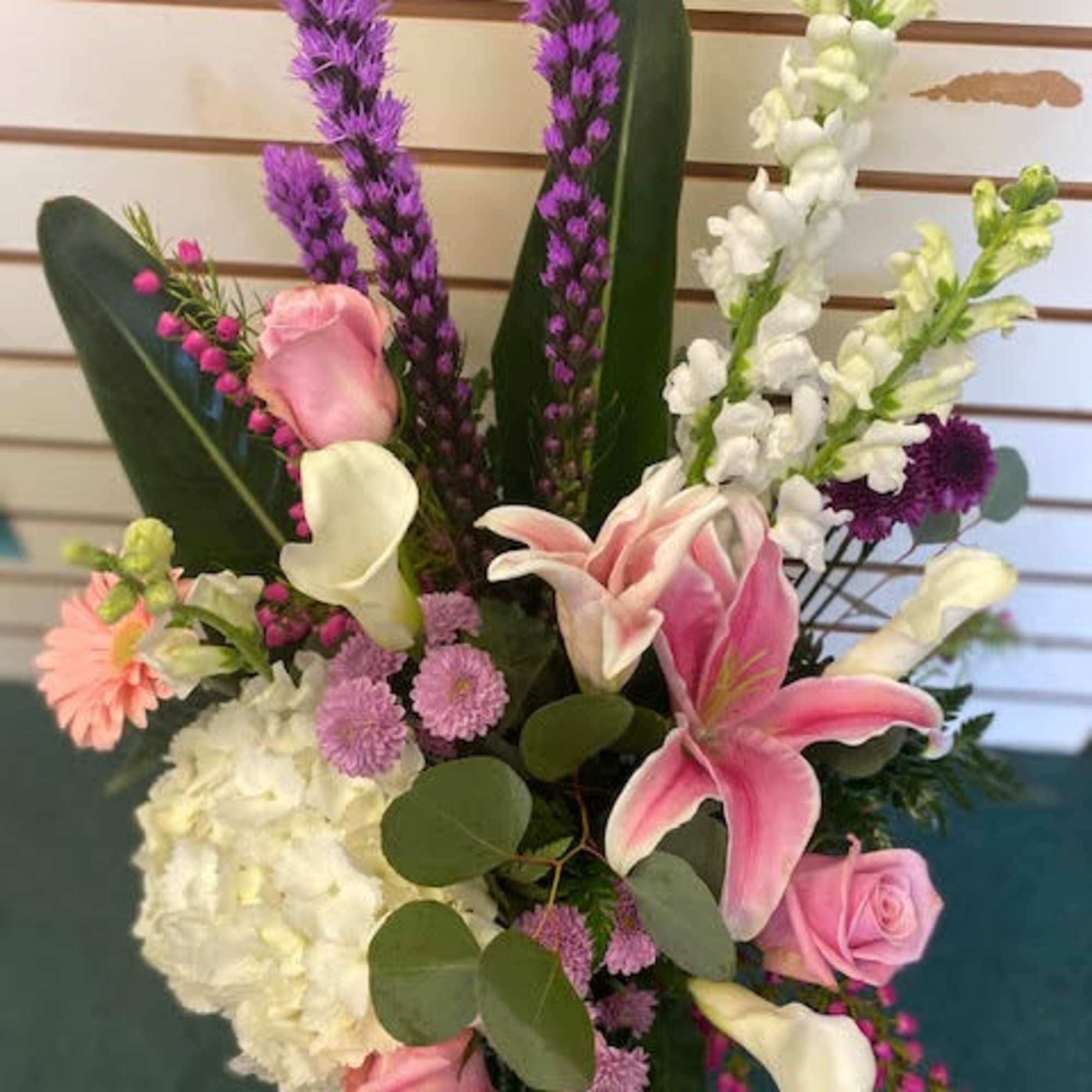 Pink and white floral arrangement with lilies, roses, and calla lilies