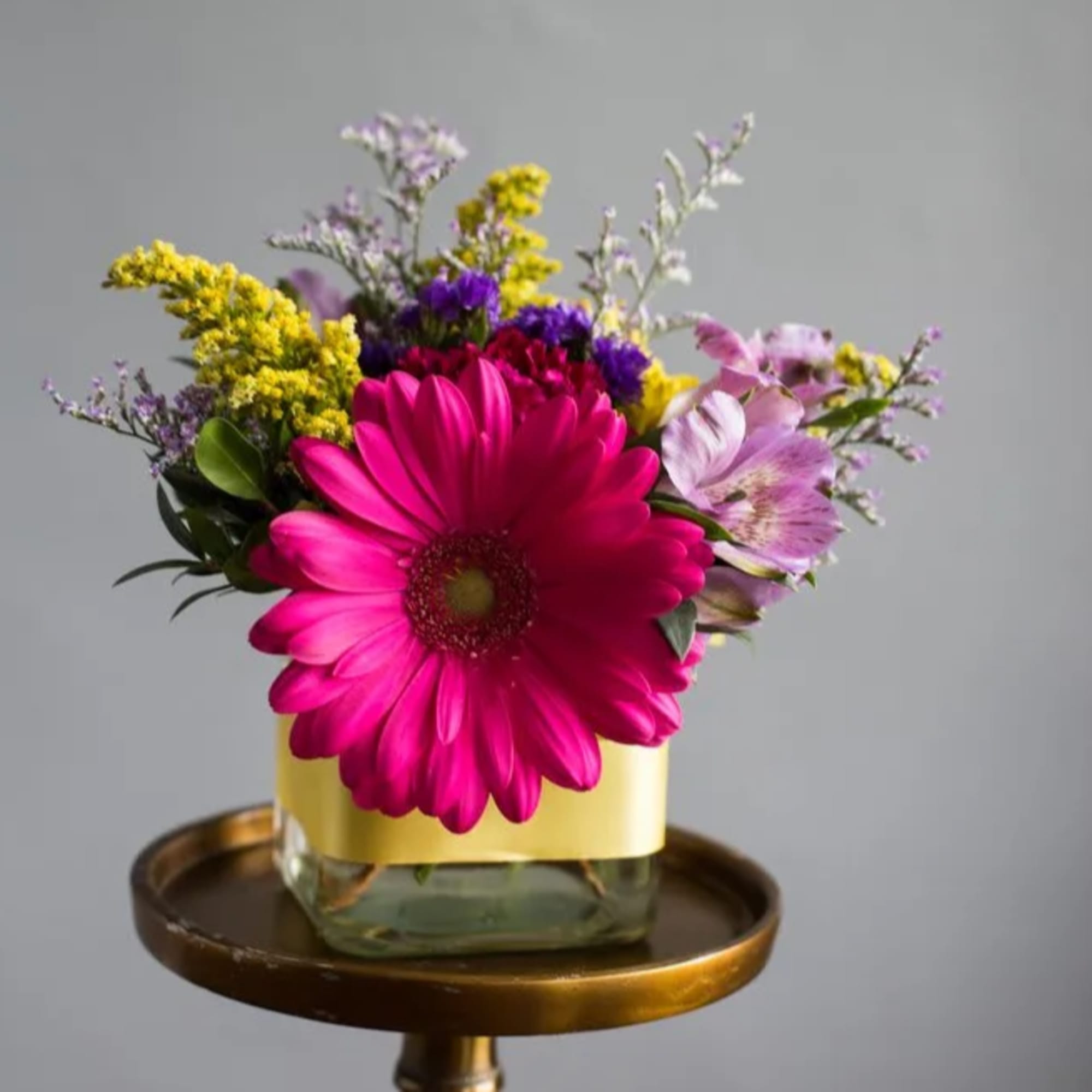 Bright arrangement featuring carnations, gerbers, alstromeria and more in a 4" glass