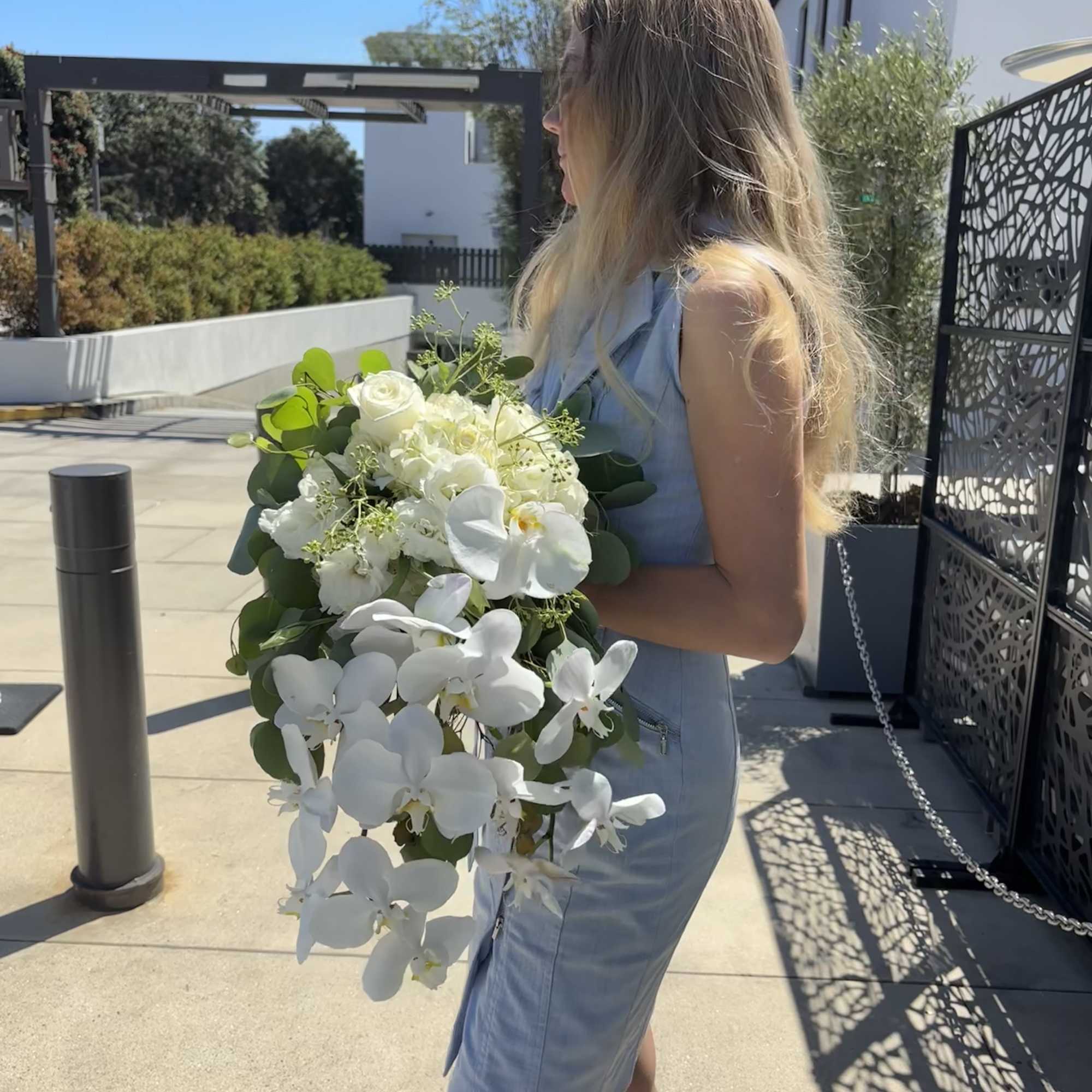 Woman holding a large bouquet of white orchids and roses