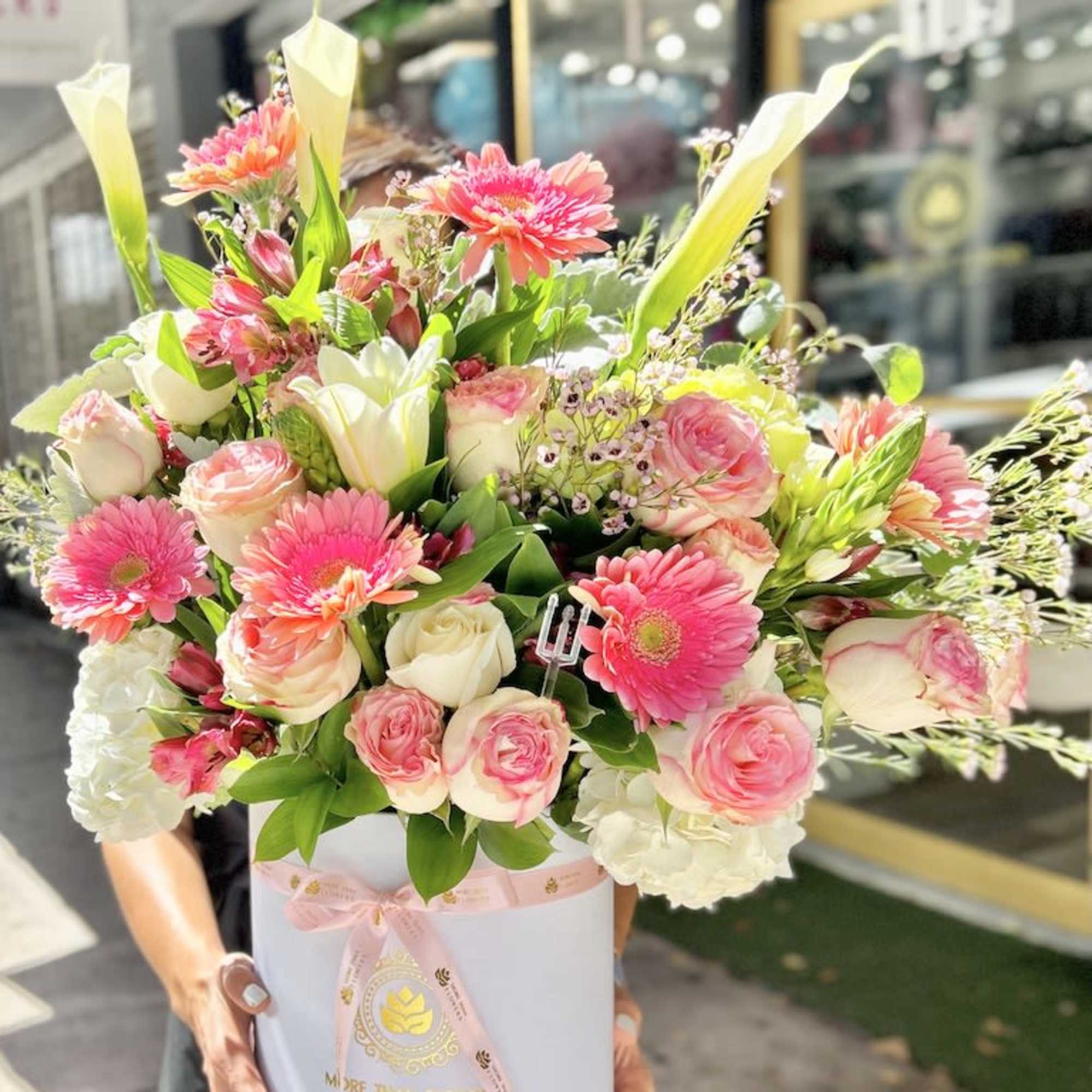 Large pink and white flower arrangement with roses, gerbera daisies, and calla lilies in a white hatbox
