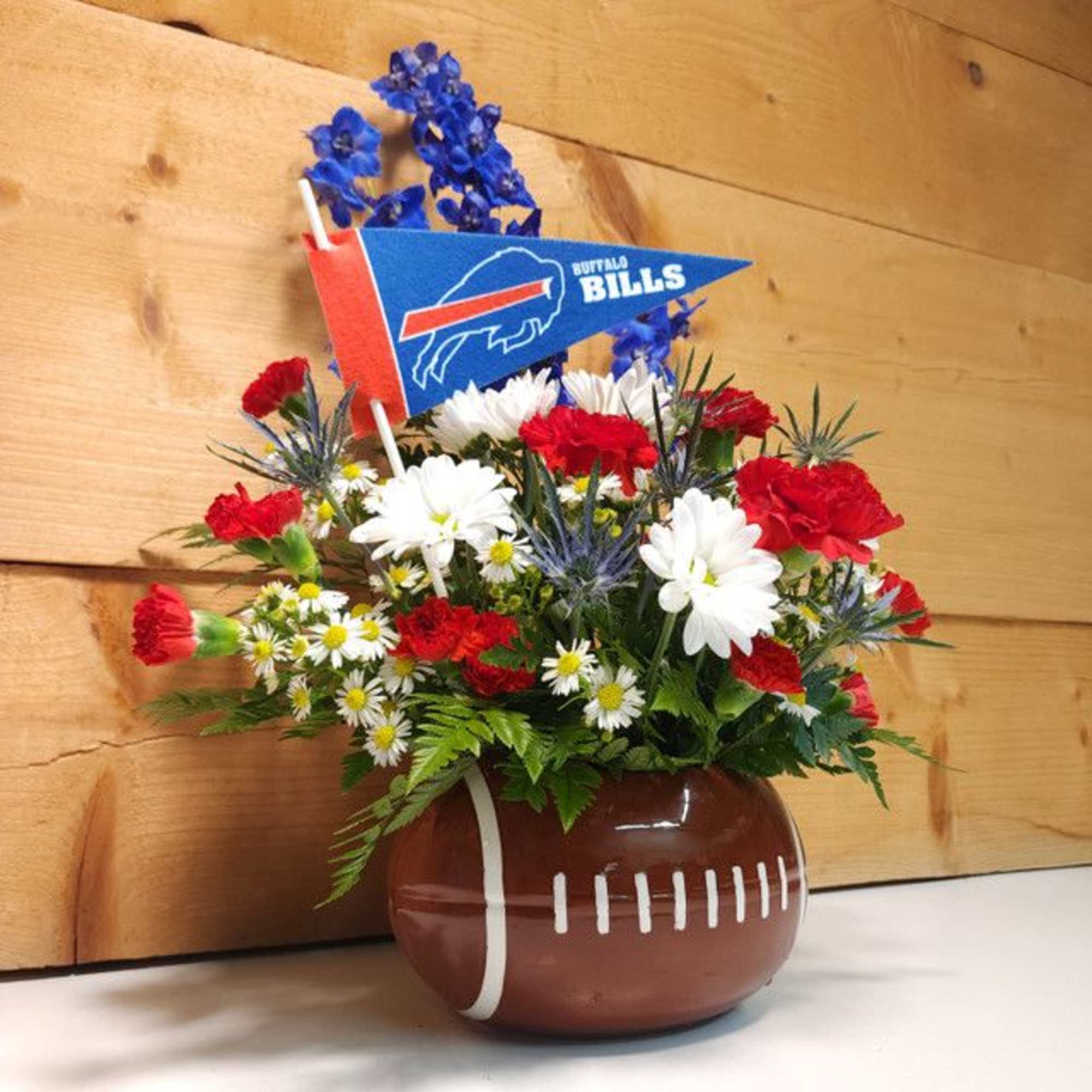 Football-themed flower arrangement in a football-shaped vase with a Buffalo Bills pennant