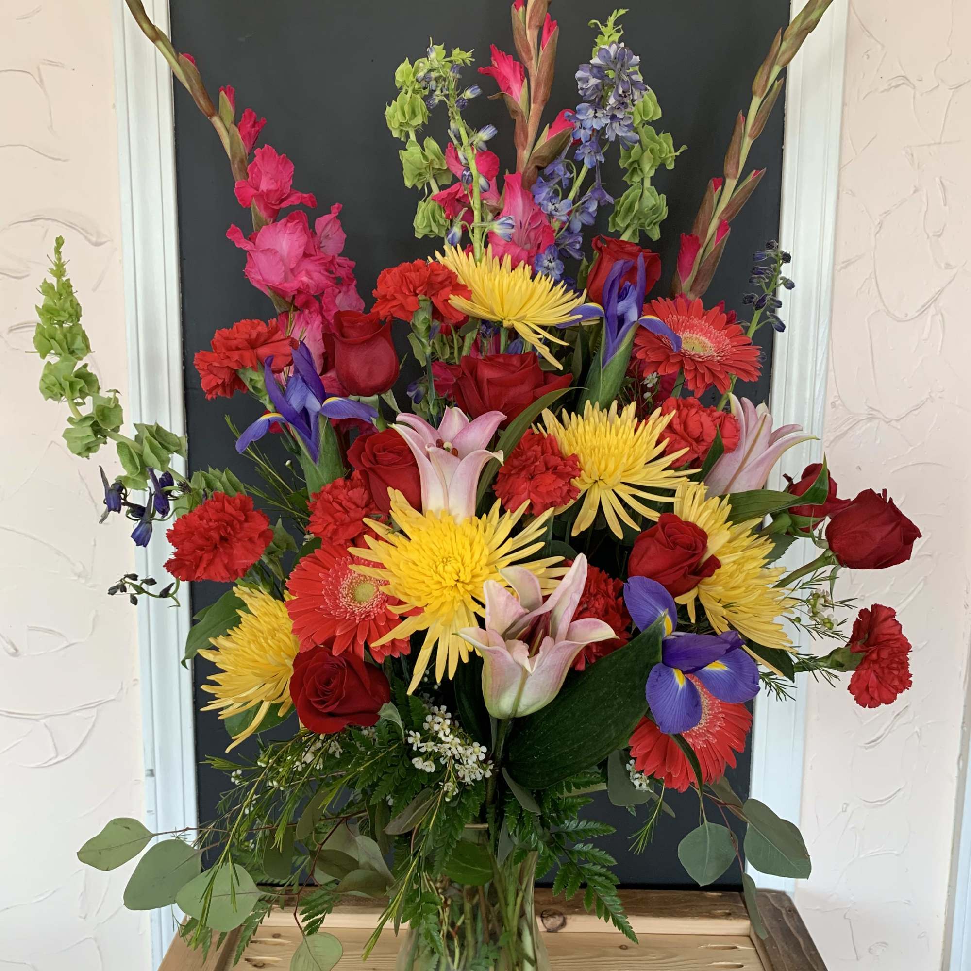 Tall mixed bouquet in a glass vase with red, yellow, pink, and purple flowers