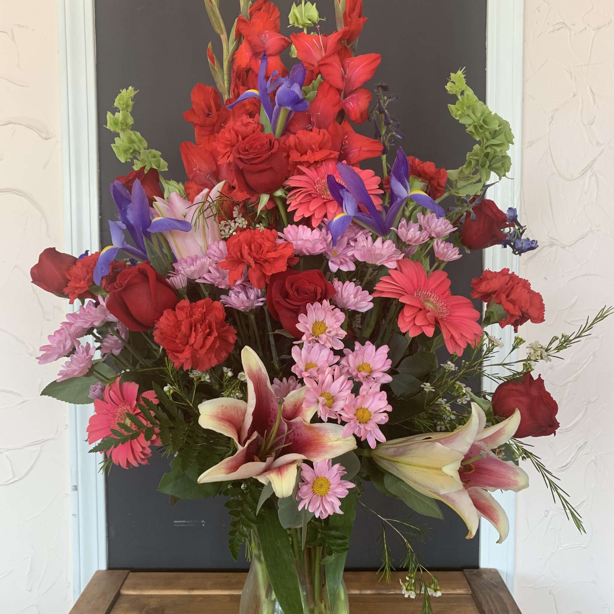Tall mixed bouquet in a glass vase with red, pink, purple, and white flowers