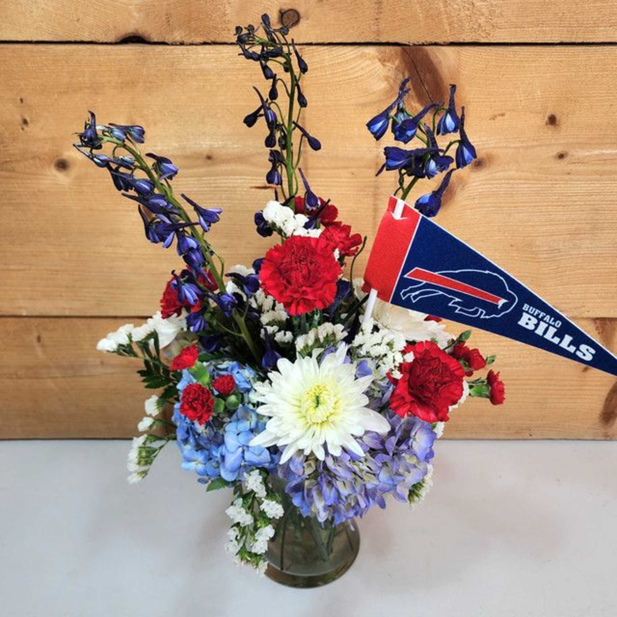 Bouquet of red, white, and blue flowers in a glass vase with a Buffalo Bills pennant