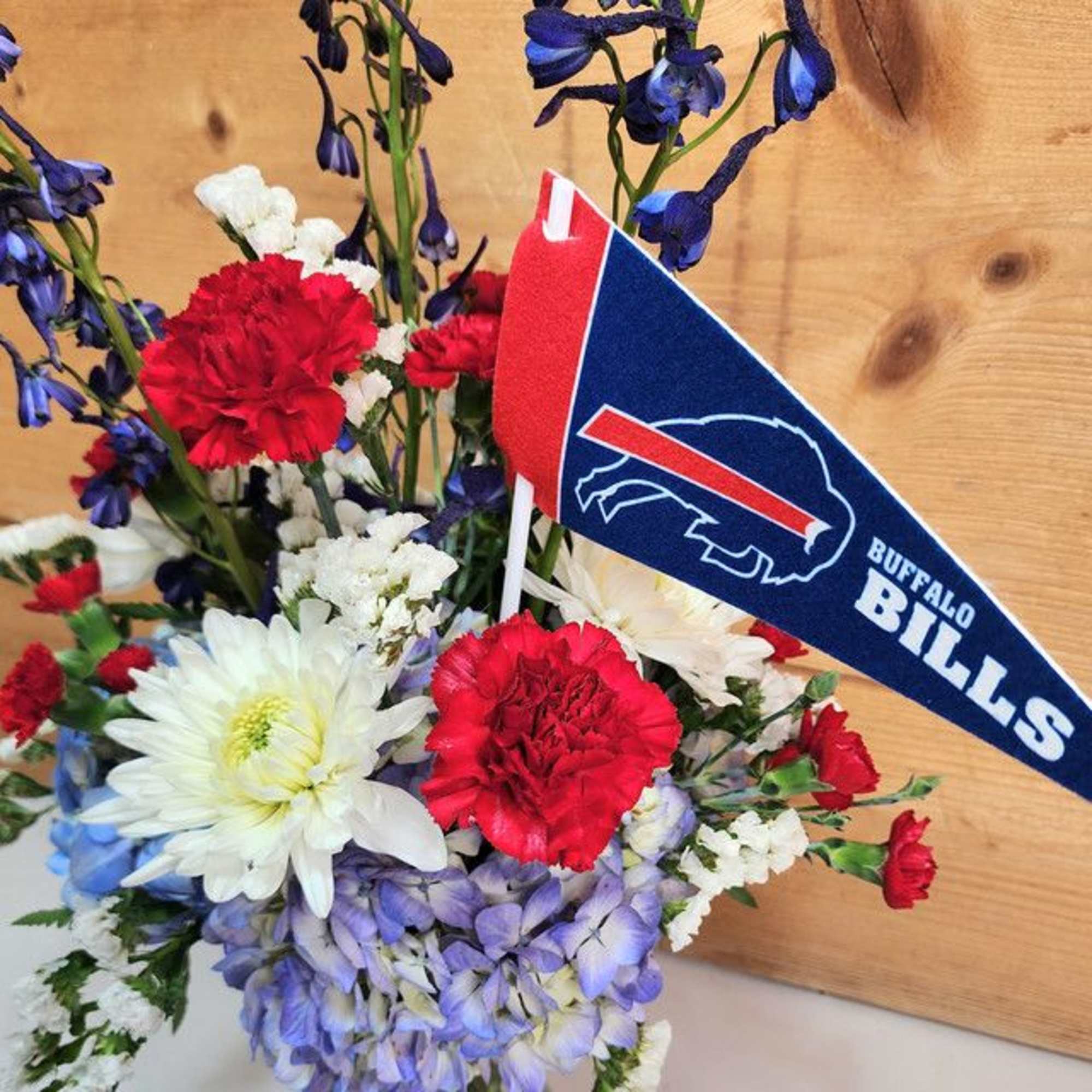 Mixed bouquet with red carnations, white daisies, and blue flowers with a Buffalo Bills pennant