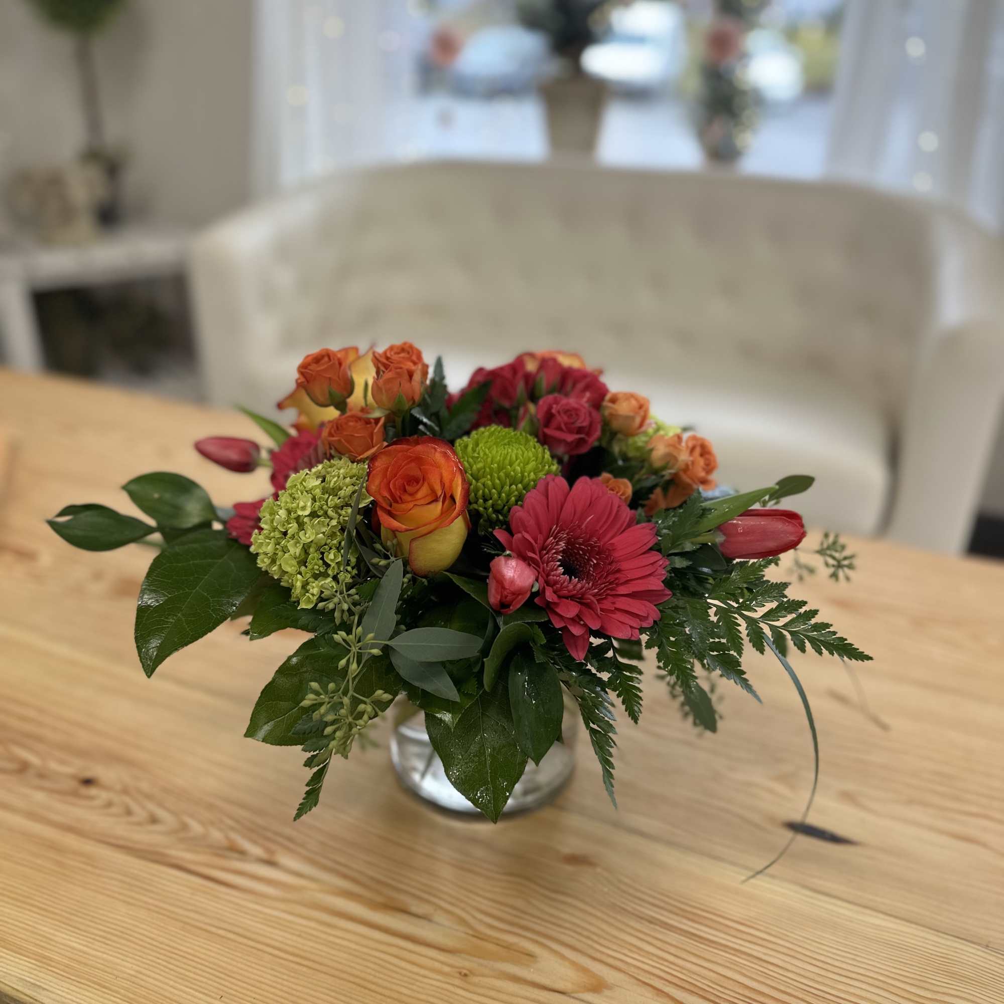 Mixed bouquet of orange and pink flowers in a clear glass vase