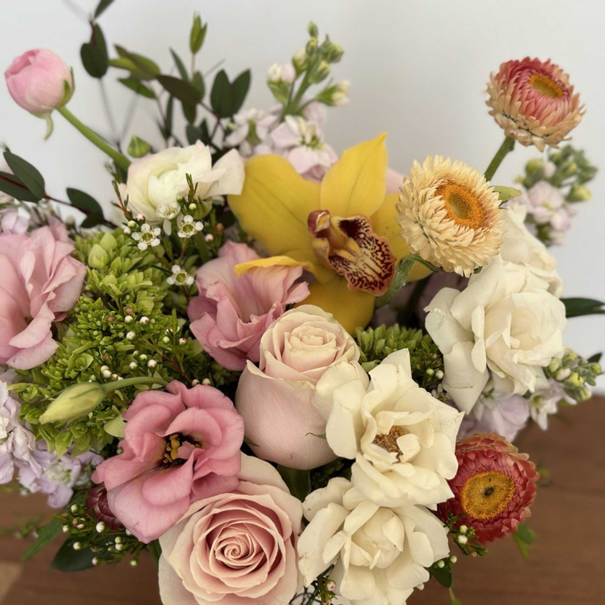 Mixed bouquet with pink and cream roses, yellow orchid, and strawflowers