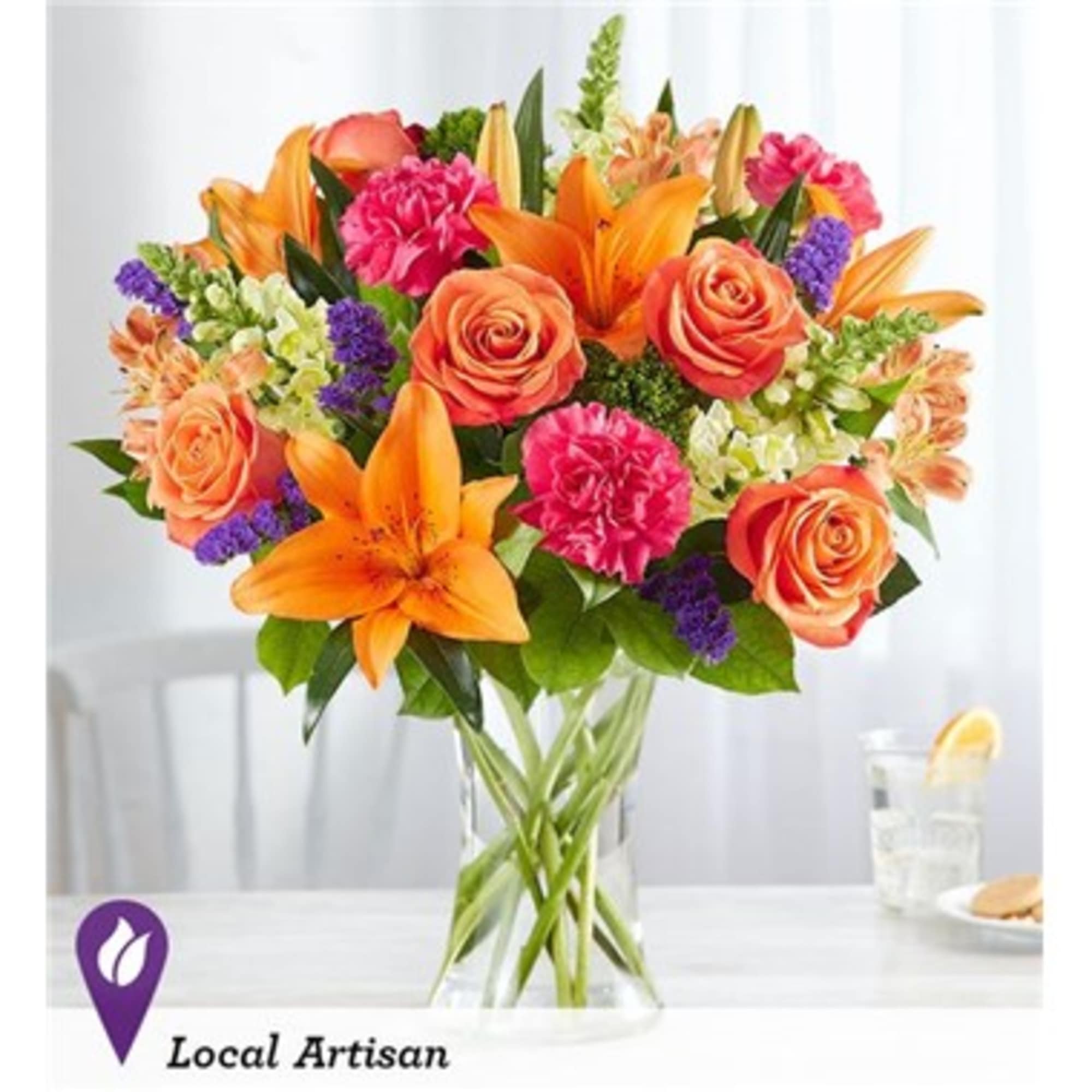 Bouquet of orange lilies, coral roses, and pink carnations in a glass vase