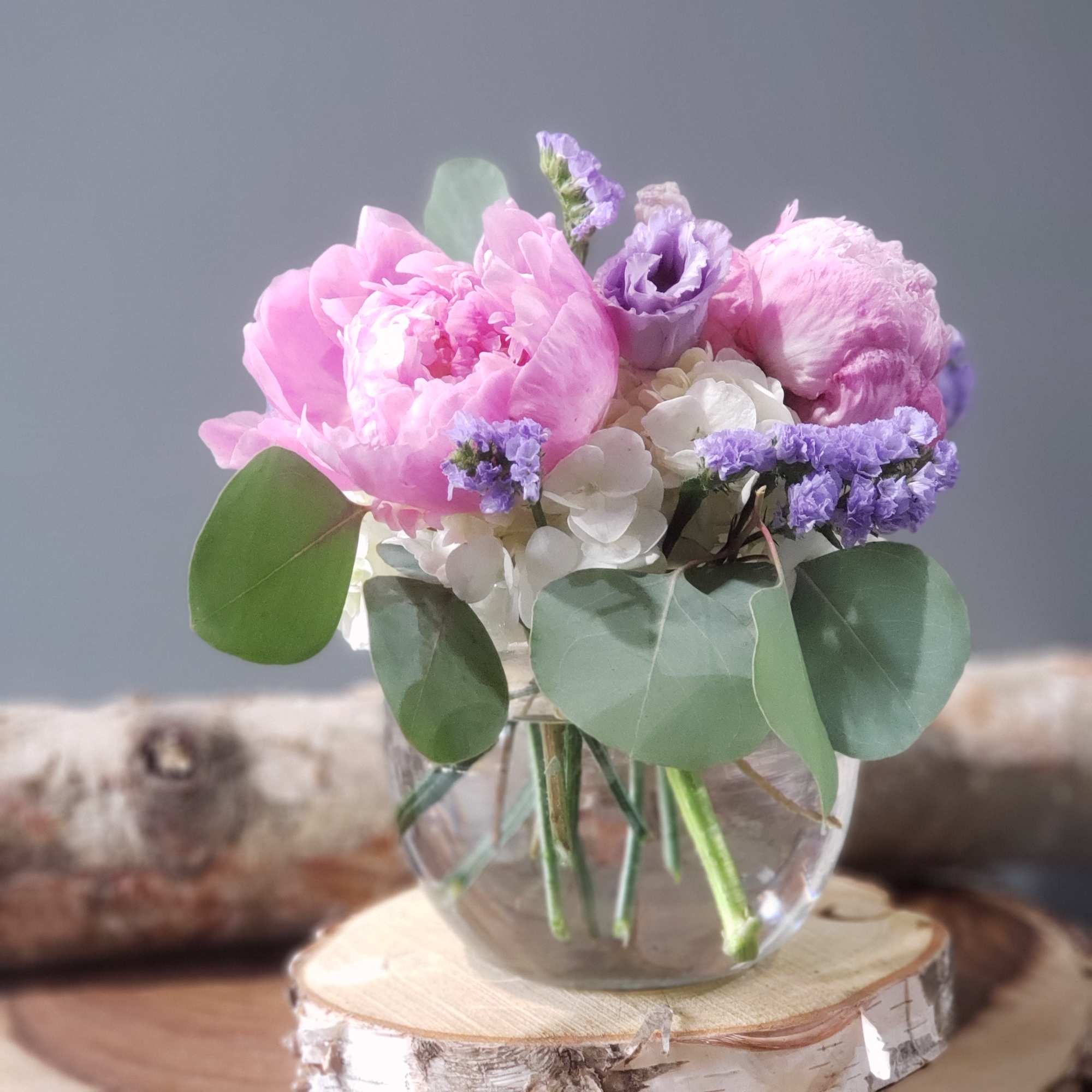 Pink and purple flowers arranged in a clear glass vase