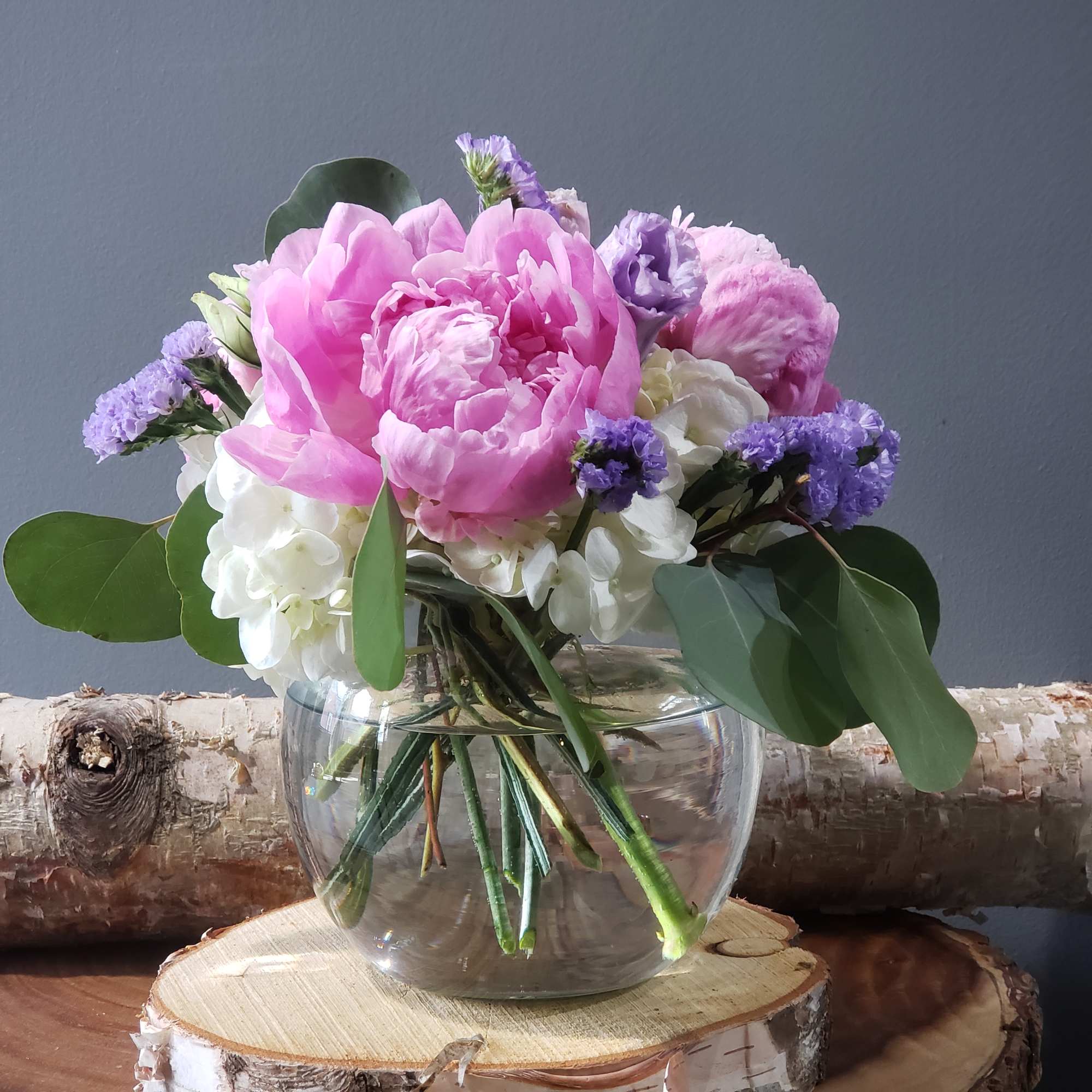 Pink peonies and white hydrangeas in a round glass vase