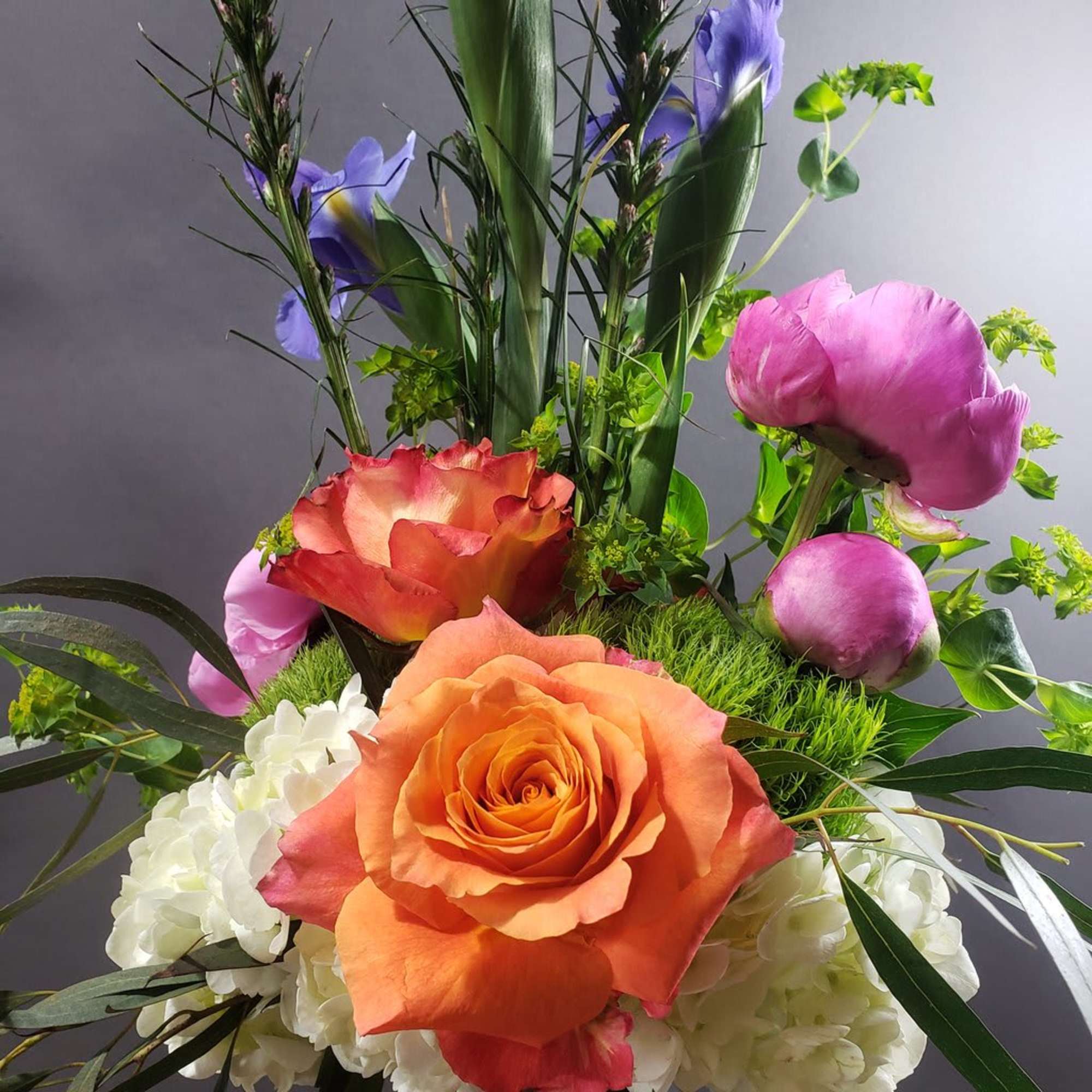Bouquet with orange and pink roses, white blooms, and purple flowers