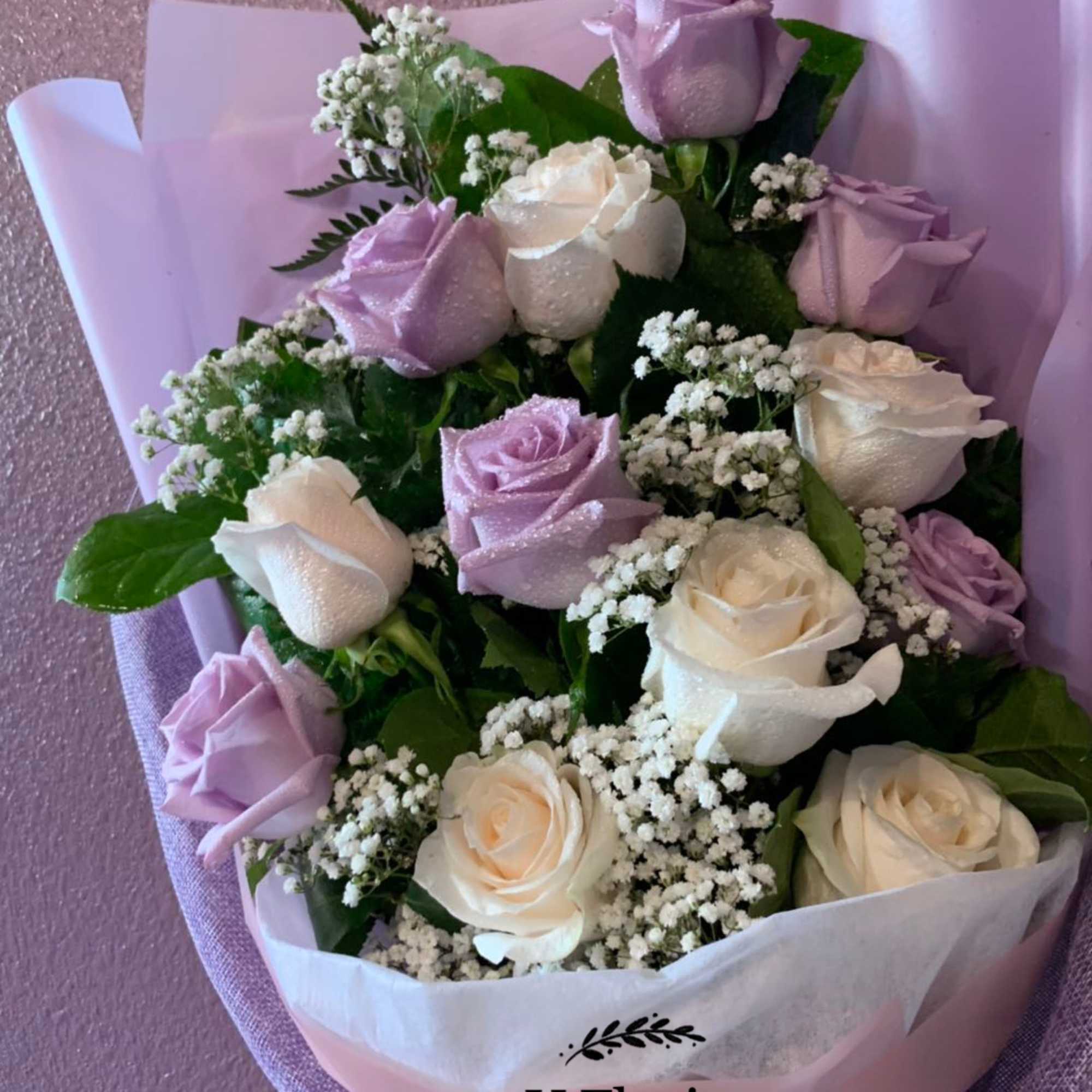 Bouquet of lavender and white roses with baby's breath in pastel wrap