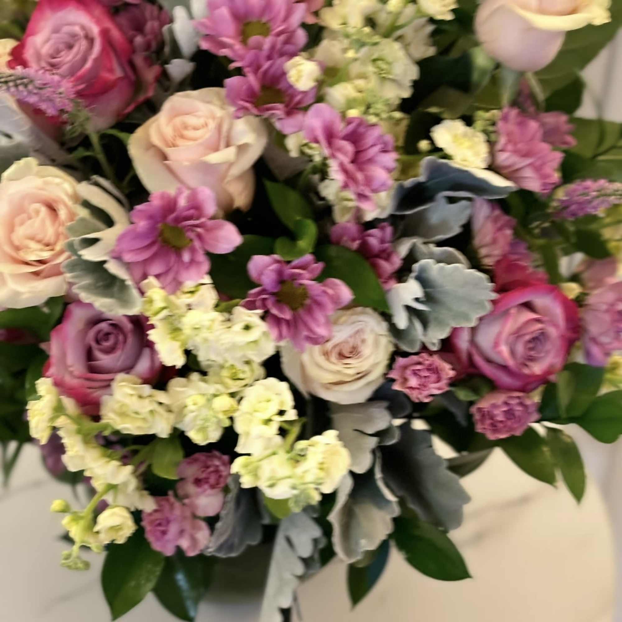 Mixed bouquet of pink and cream roses with purple daisies