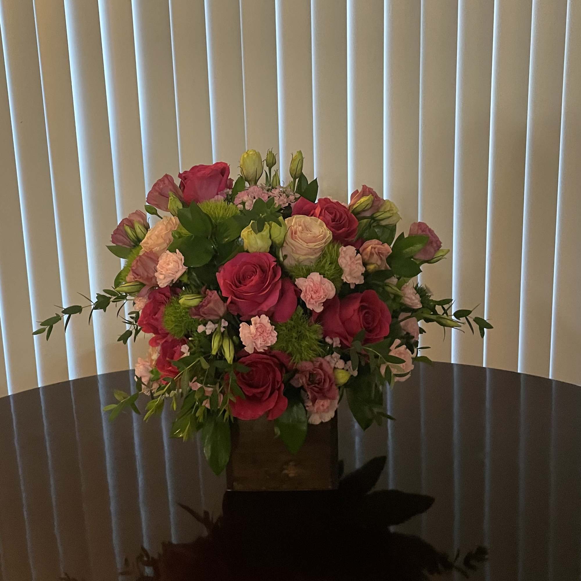 Bouquet of pink and red roses with small pink flowers in a wooden box
