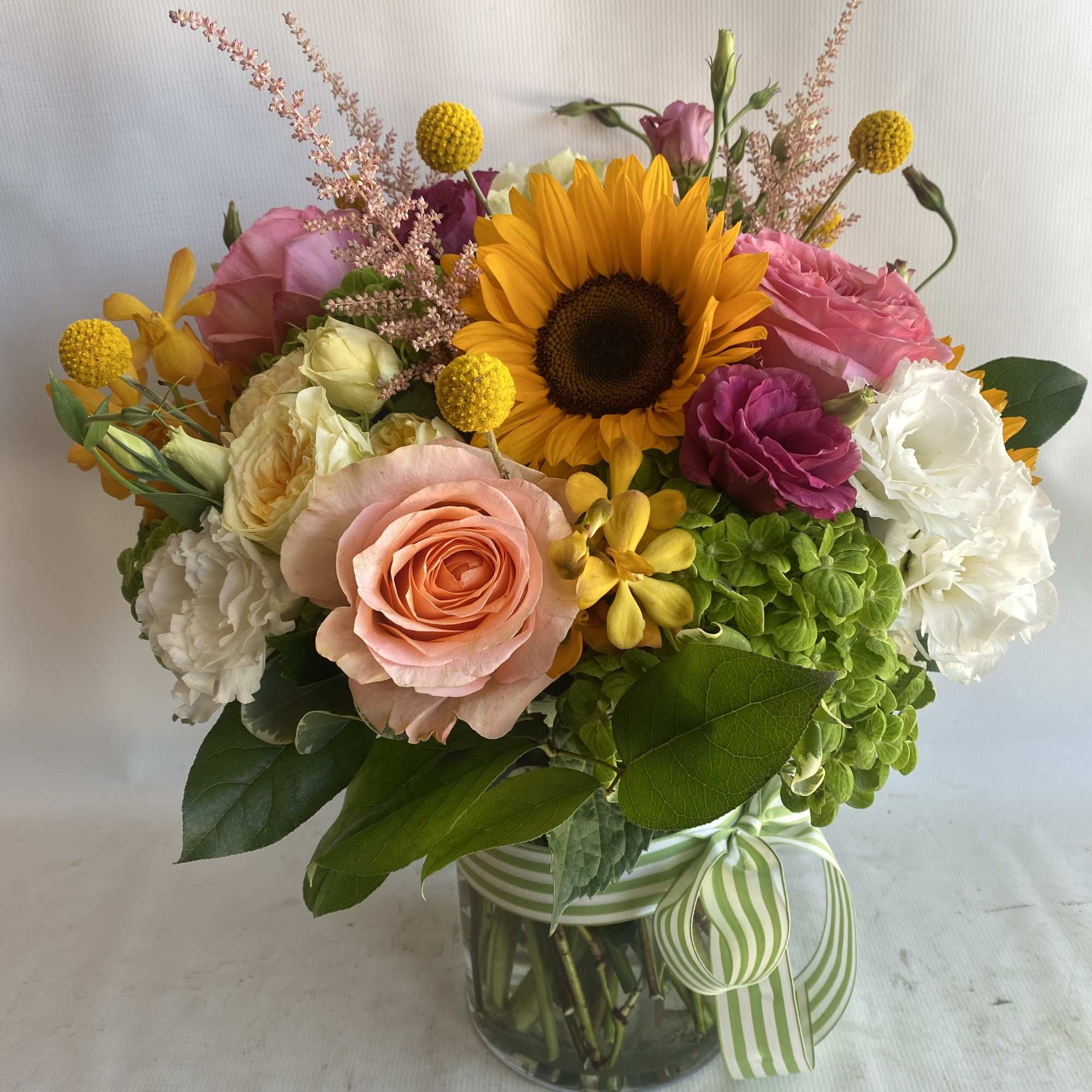 Mixed bouquet with a sunflower, roses, hydrangea, and a glass vase