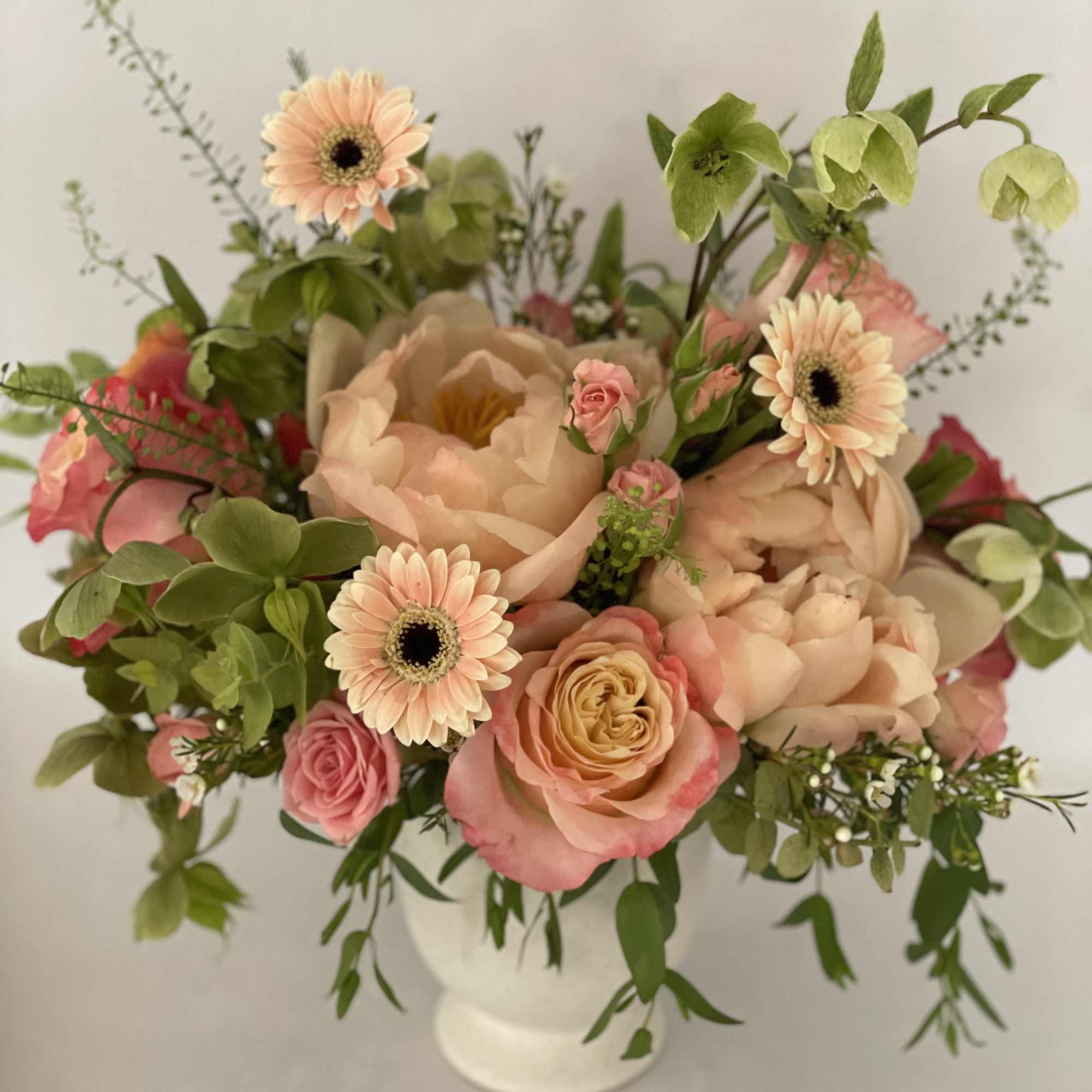 Peach and pink floral arrangement in a white vase
