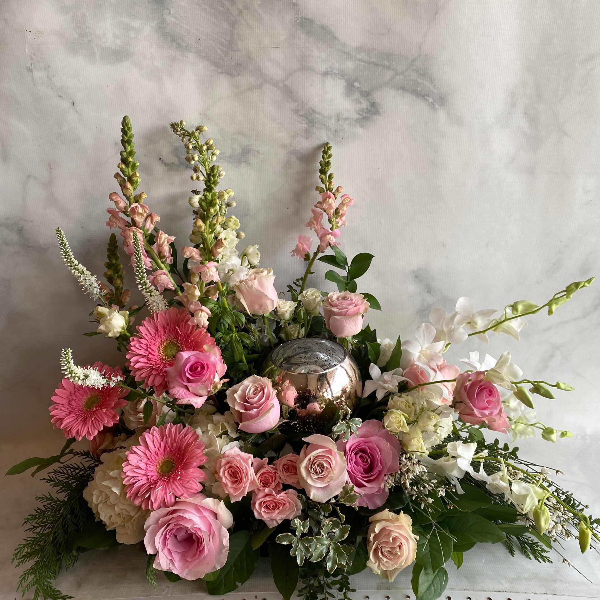 Pink and white floral arrangement with roses, gerbera daisies, and orchids in a metallic vase