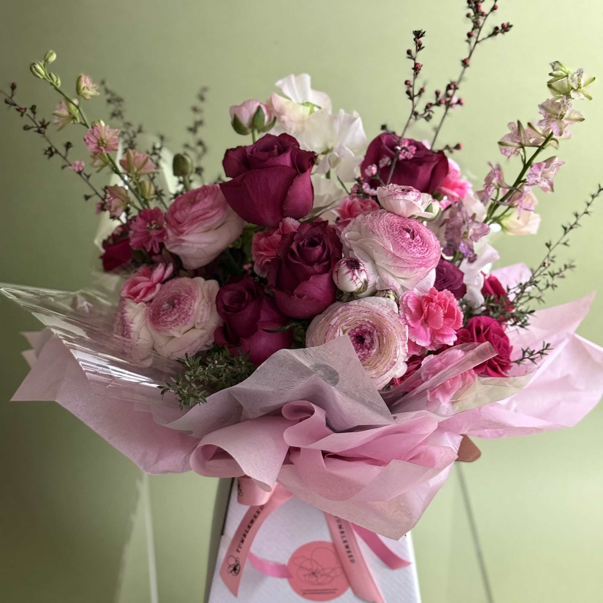 Pink and white bouquet of roses and ranunculus in pink wrapping