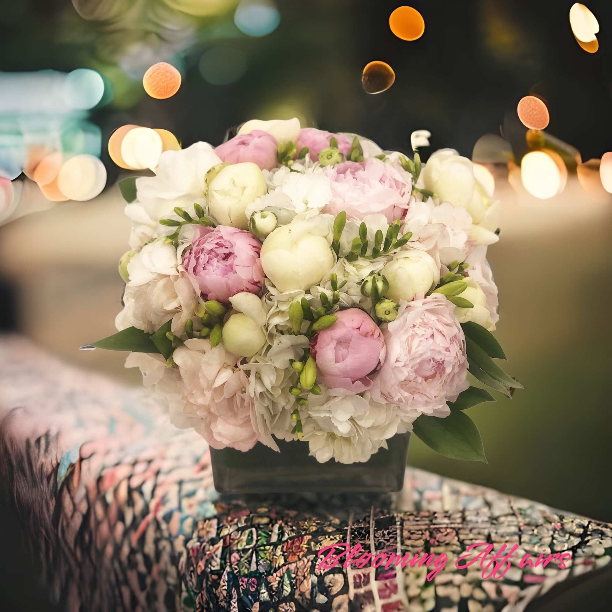Bouquet of pink and white peonies in a dark square vase
