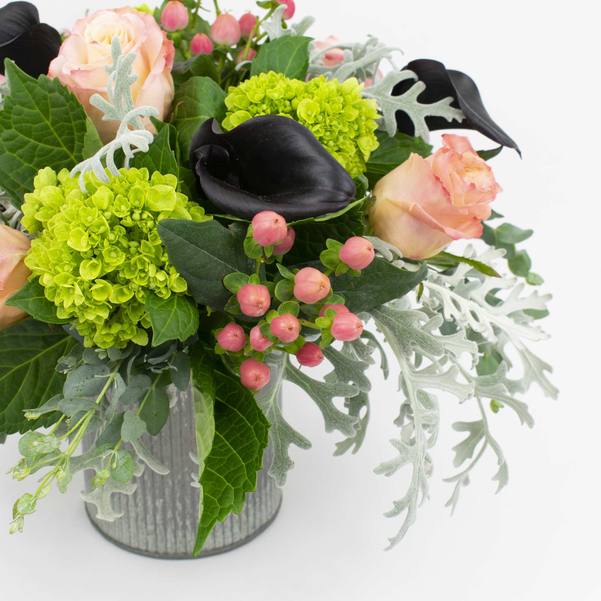 Peach roses and black calla lilies in a silver vase