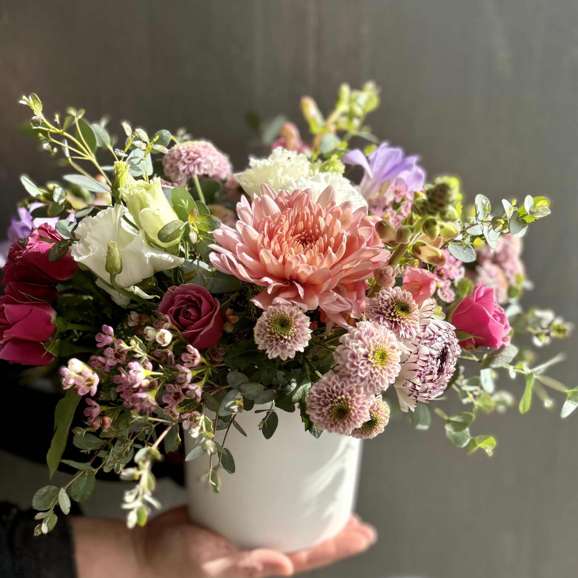 Mixed pink and white flowers arranged in a white vase