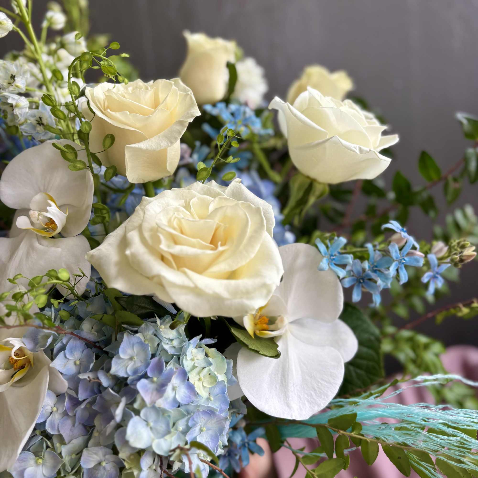 Bouquet of white roses, white orchids, and blue hydrangeas