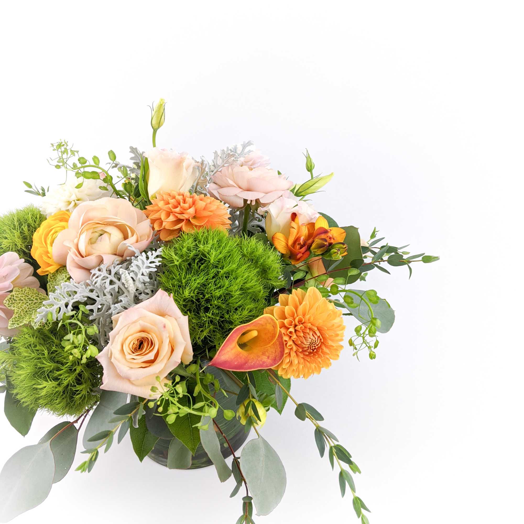 Mixed bouquet in a glass vase with peach, orange, and green blooms