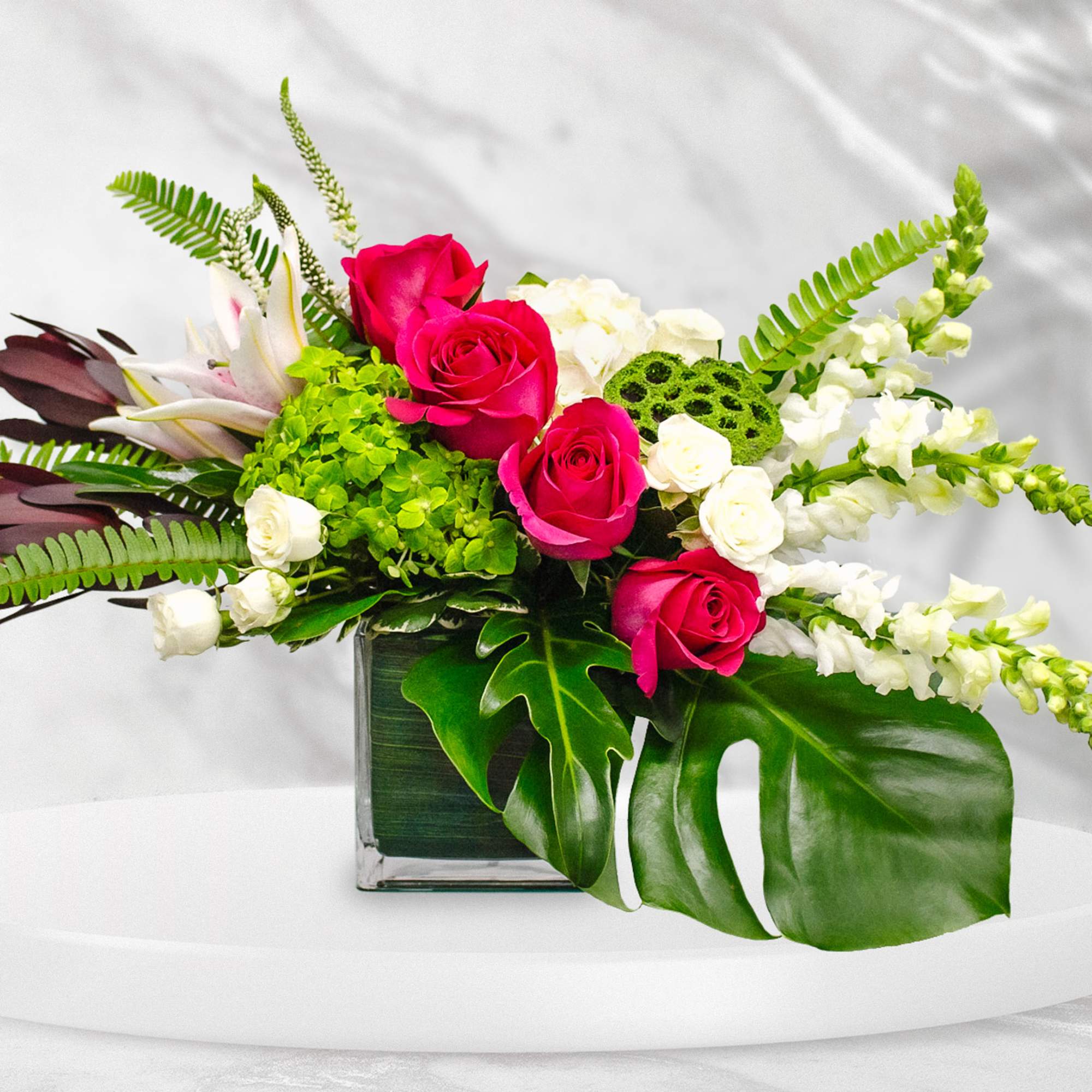 Pink roses and white flowers in a square glass vase