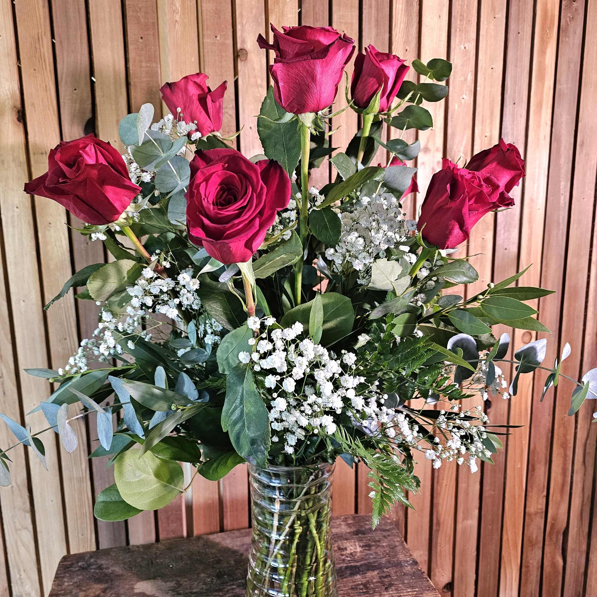 Bouquet of red roses with baby's breath in a clear glass vase