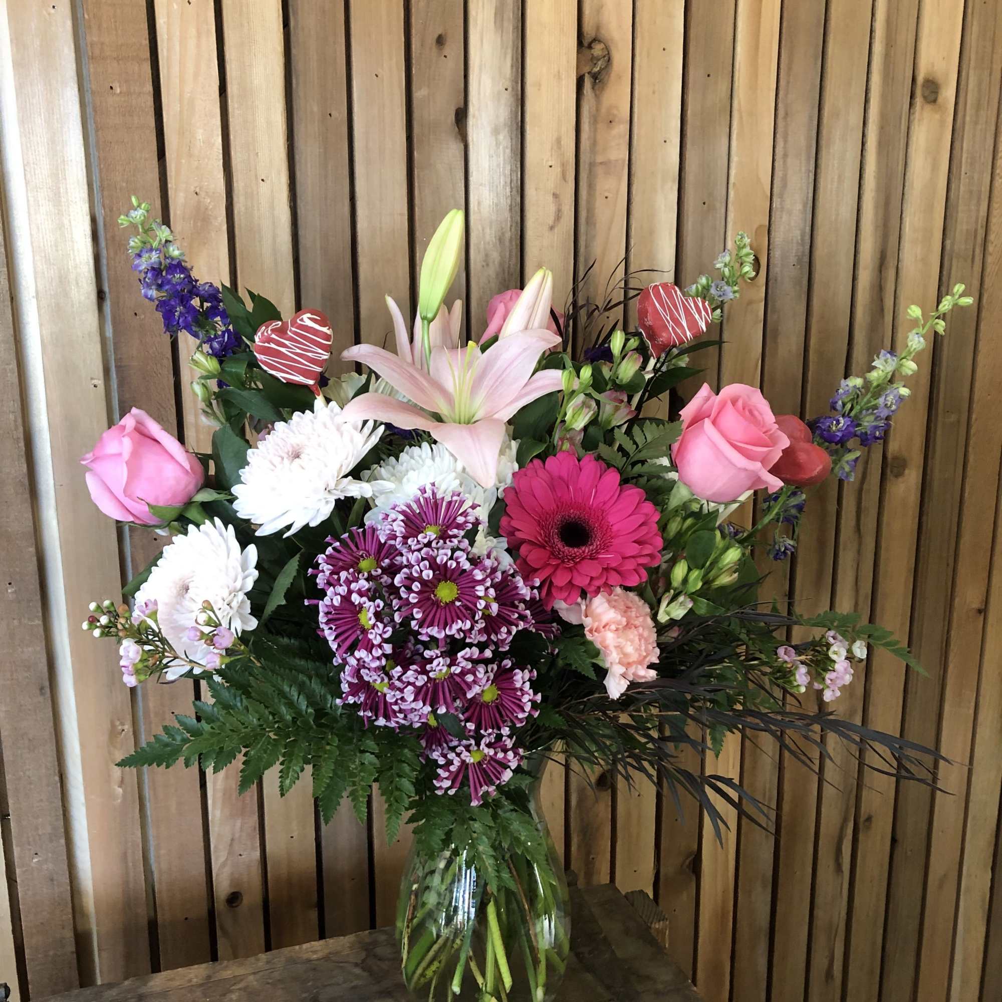 Mixed bouquet in a glass vase with pink roses, lilies, and purple blooms