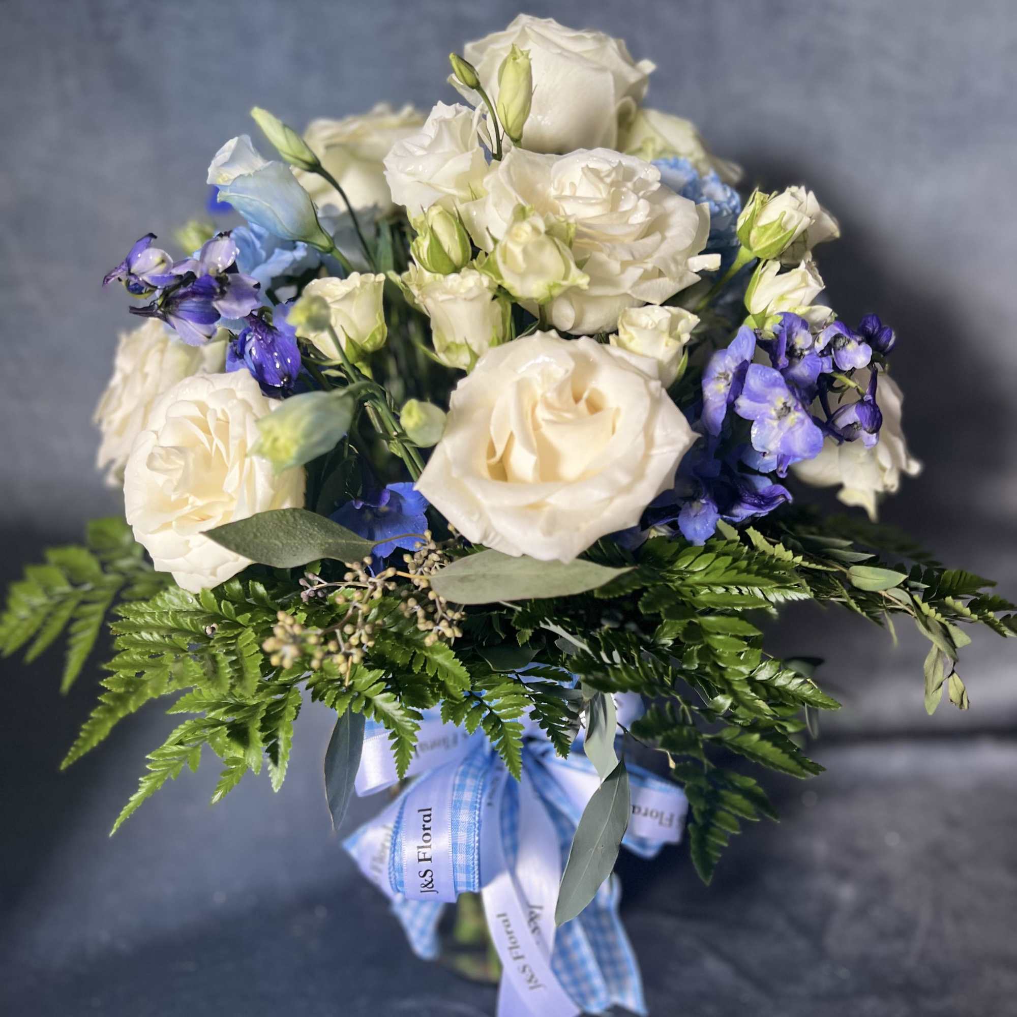 Bouquet of white roses and blue-purple flowers with greenery