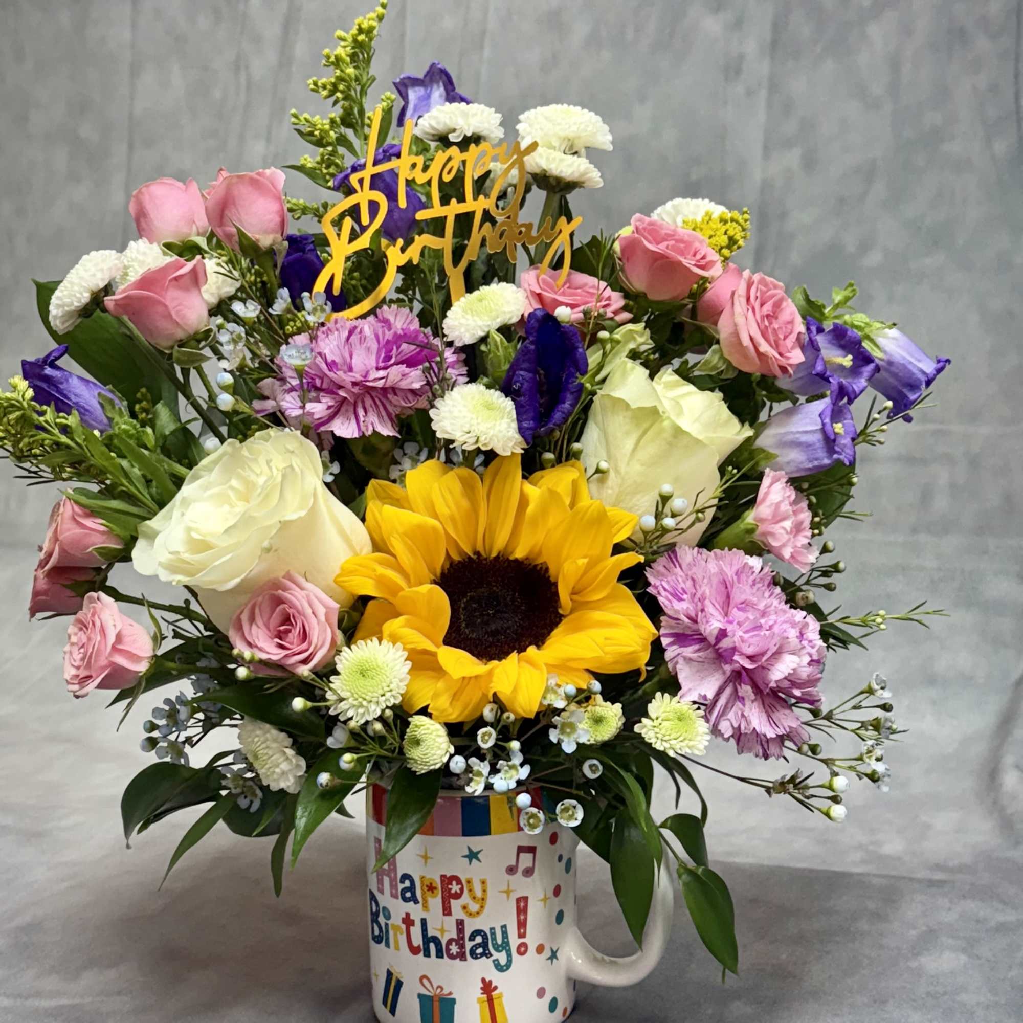 Birthday bouquet in a mug with sunflowers, roses, and mixed blooms
