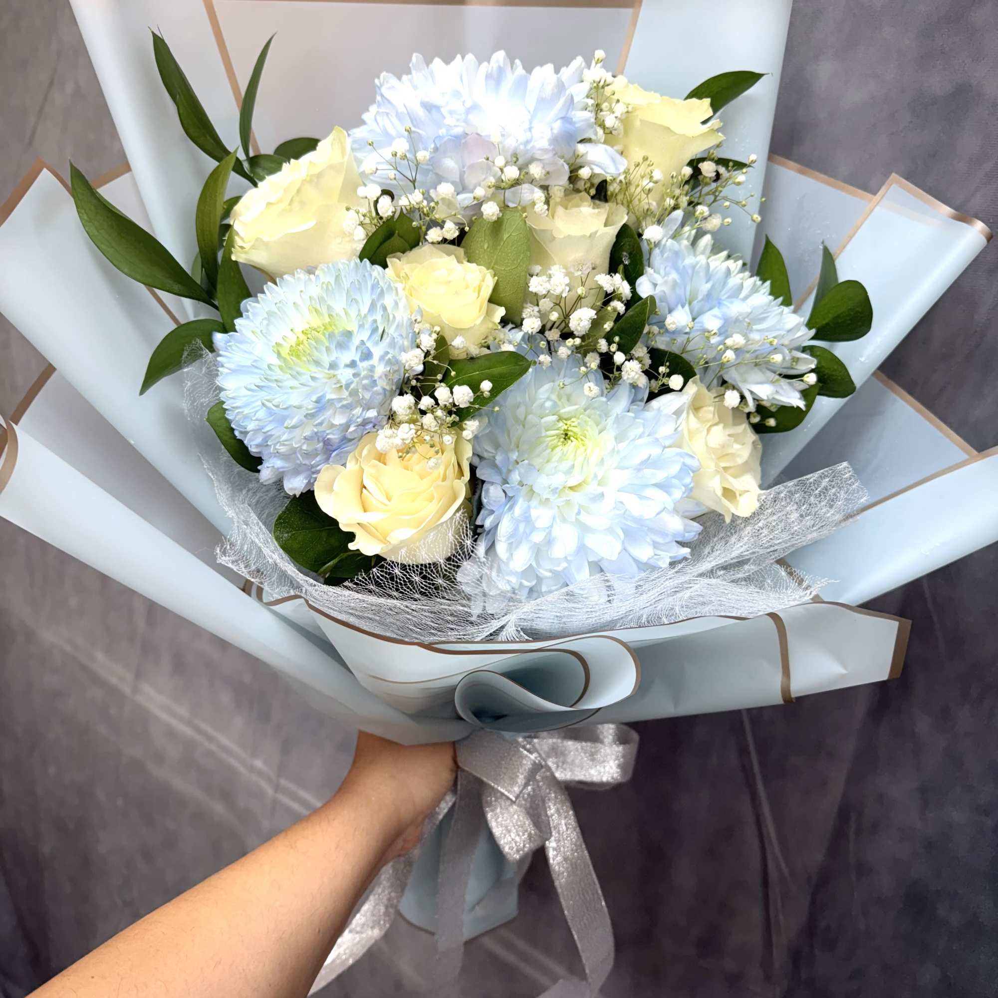 Bouquet of pale blue and cream flowers wrapped in light blue paper