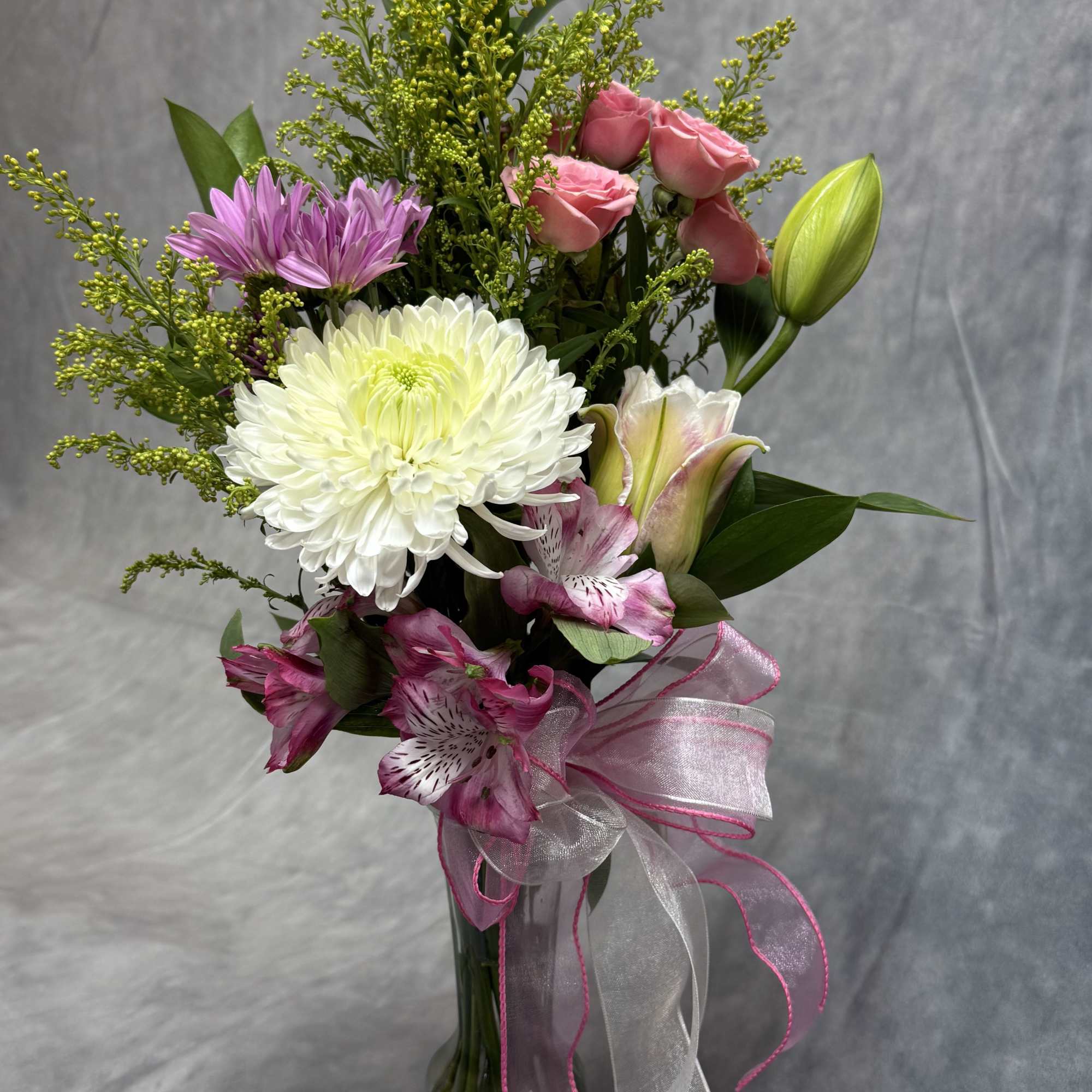 Bouquet of pink roses, white chrysanthemum, and lilies in a glass vase