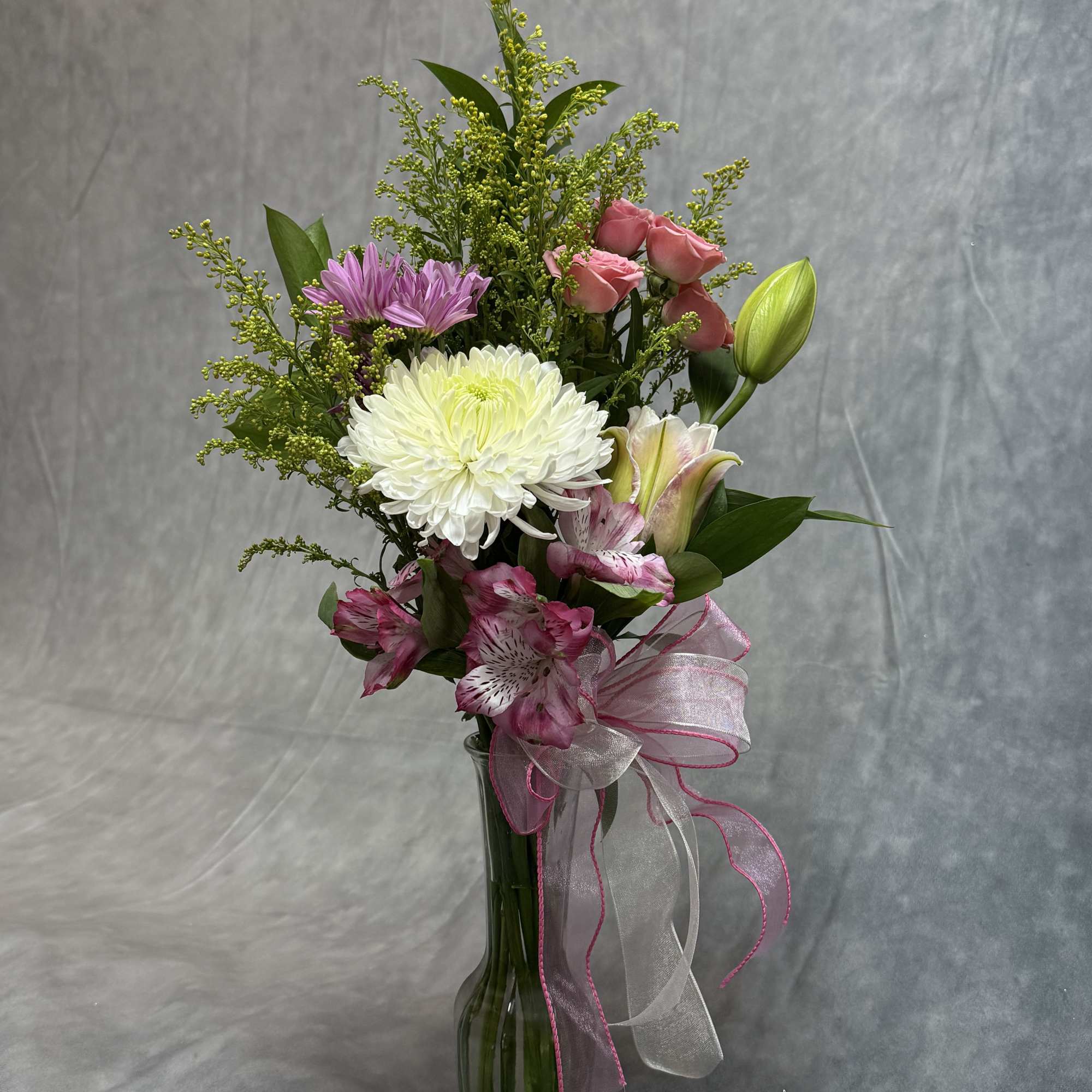 Mixed bouquet in a tall glass vase with pink and white flowers and a ribbon