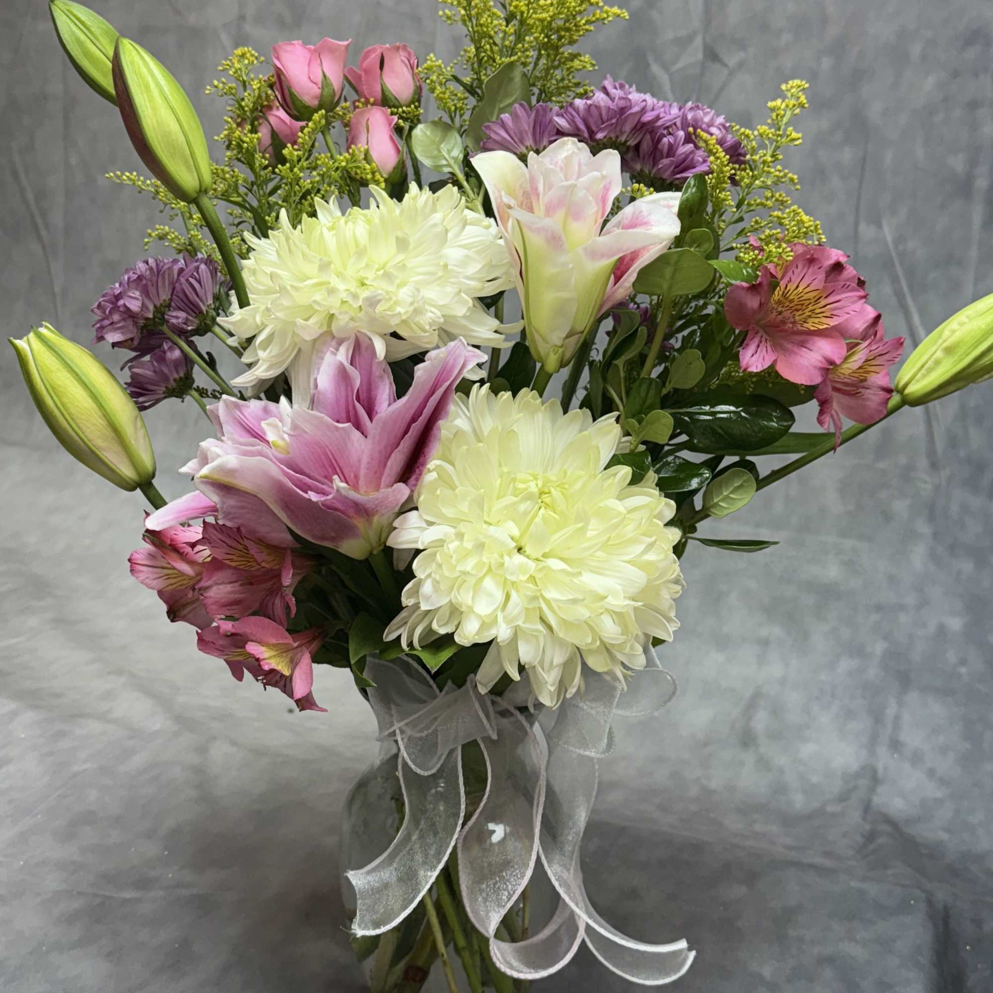 Bouquet of pink and white flowers in a glass vase with a sheer ribbon