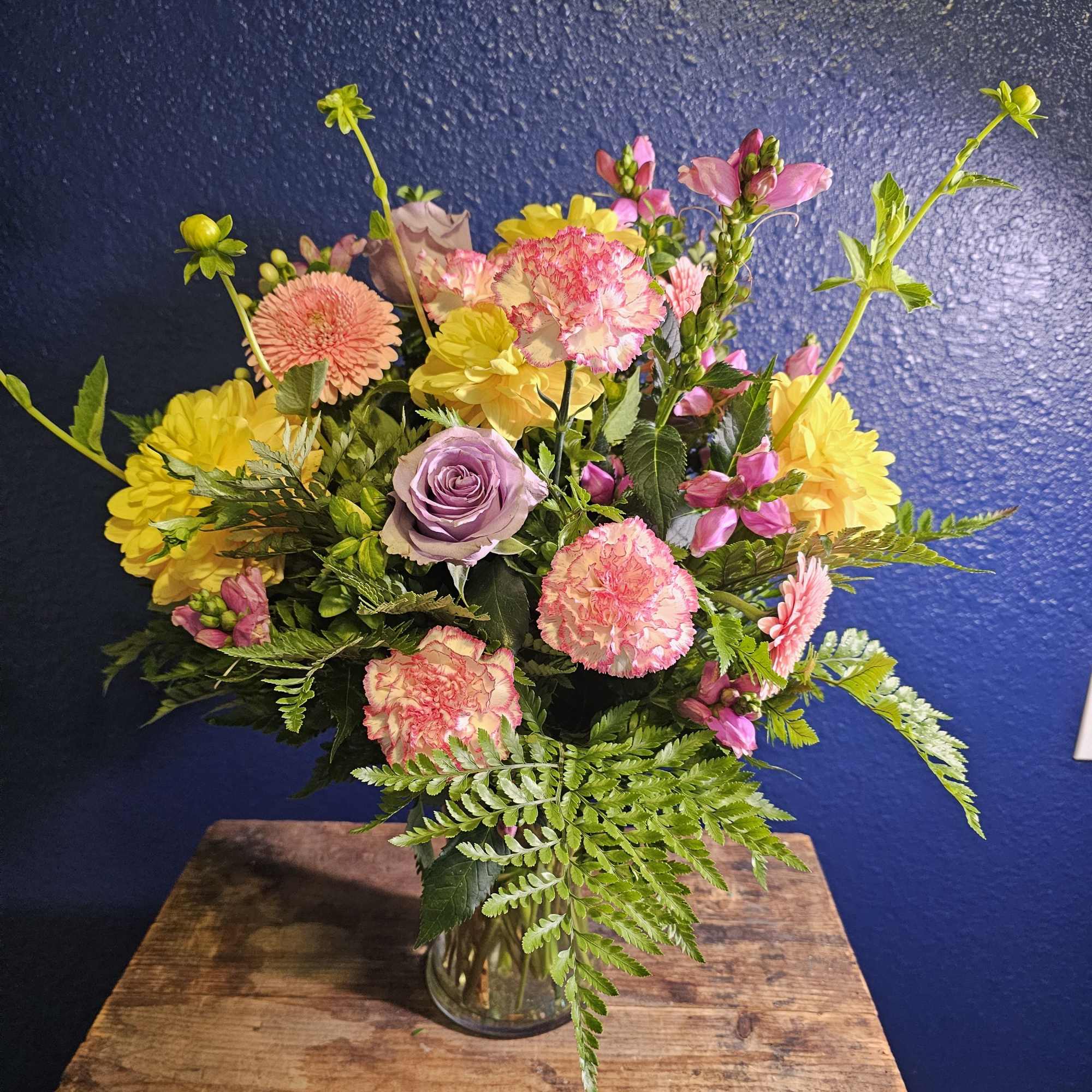 Mixed bouquet in a clear glass vase with pink, yellow, and lavender blooms