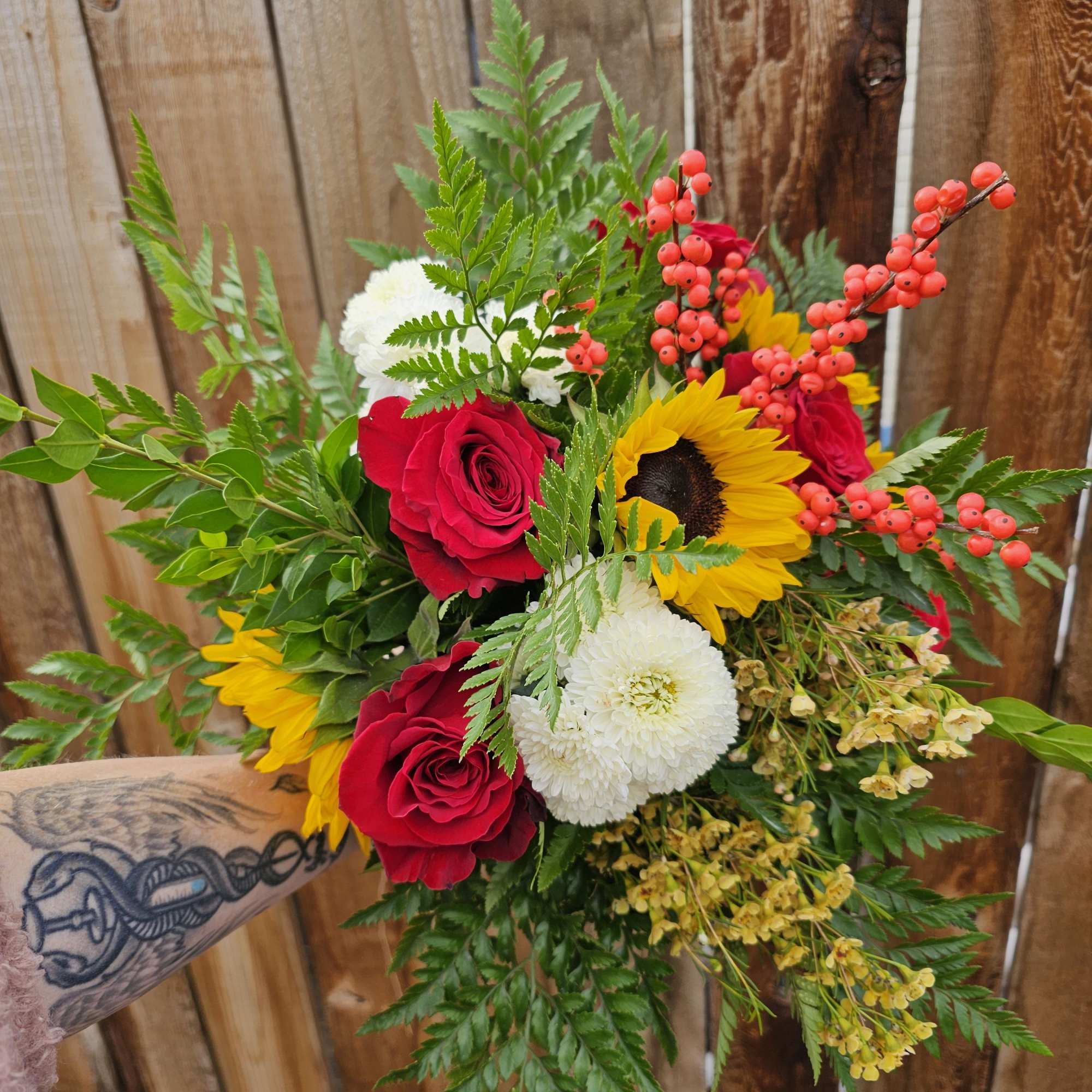Bouquet of red roses, sunflowers, and white mums with berry accents